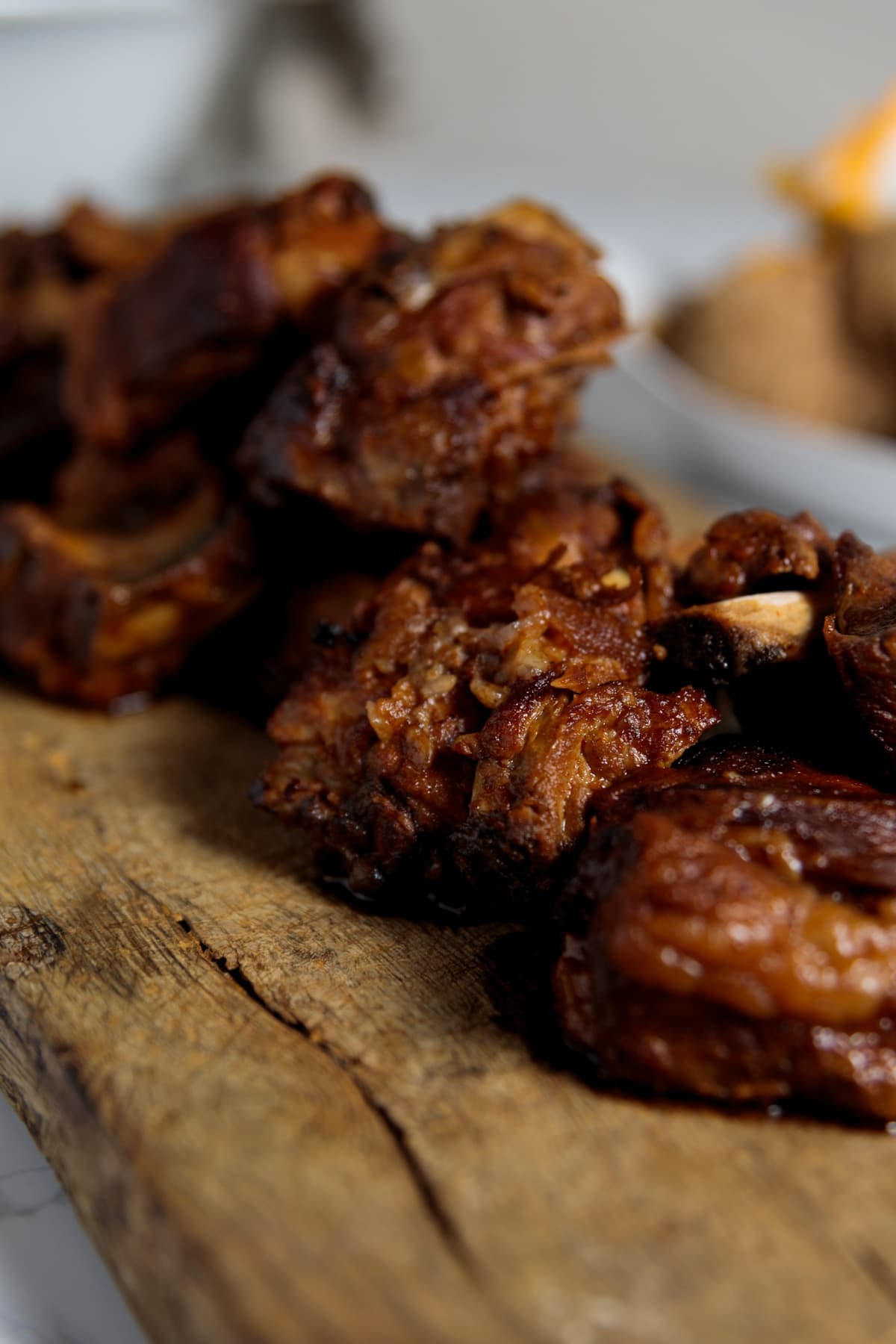 Texture of the skin on short ribs on wooden cutting board with bbq sauce all over.