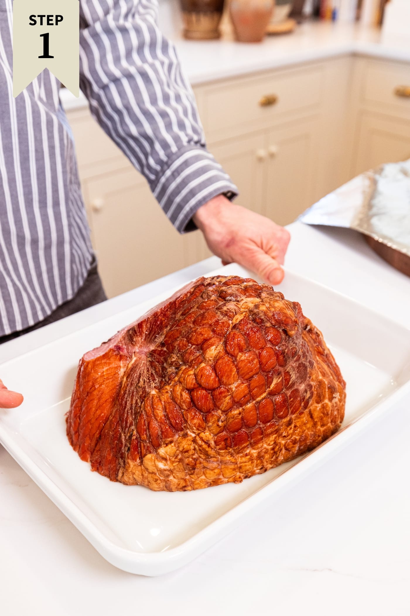 White baking pan filled with cured ham before going into the oven to bake.