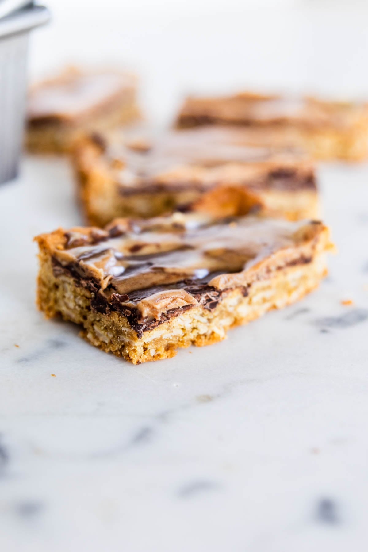Rectangular-shaped peanut butter fingers with oat base and layers of chocolate and peanut butter sitting on a marble surface.