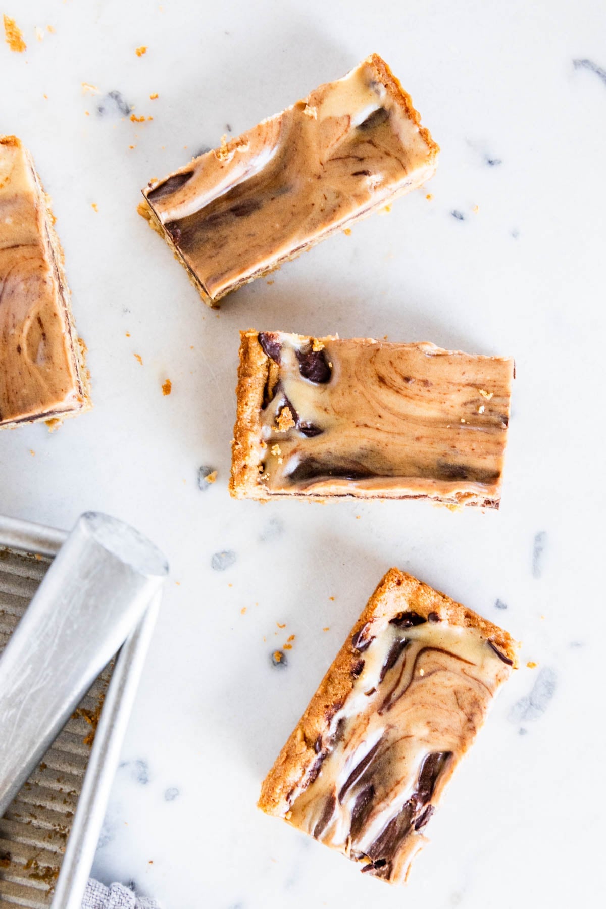 Pieces of peanut butter fingers with chocolate swirled on top sitting on marble surface.