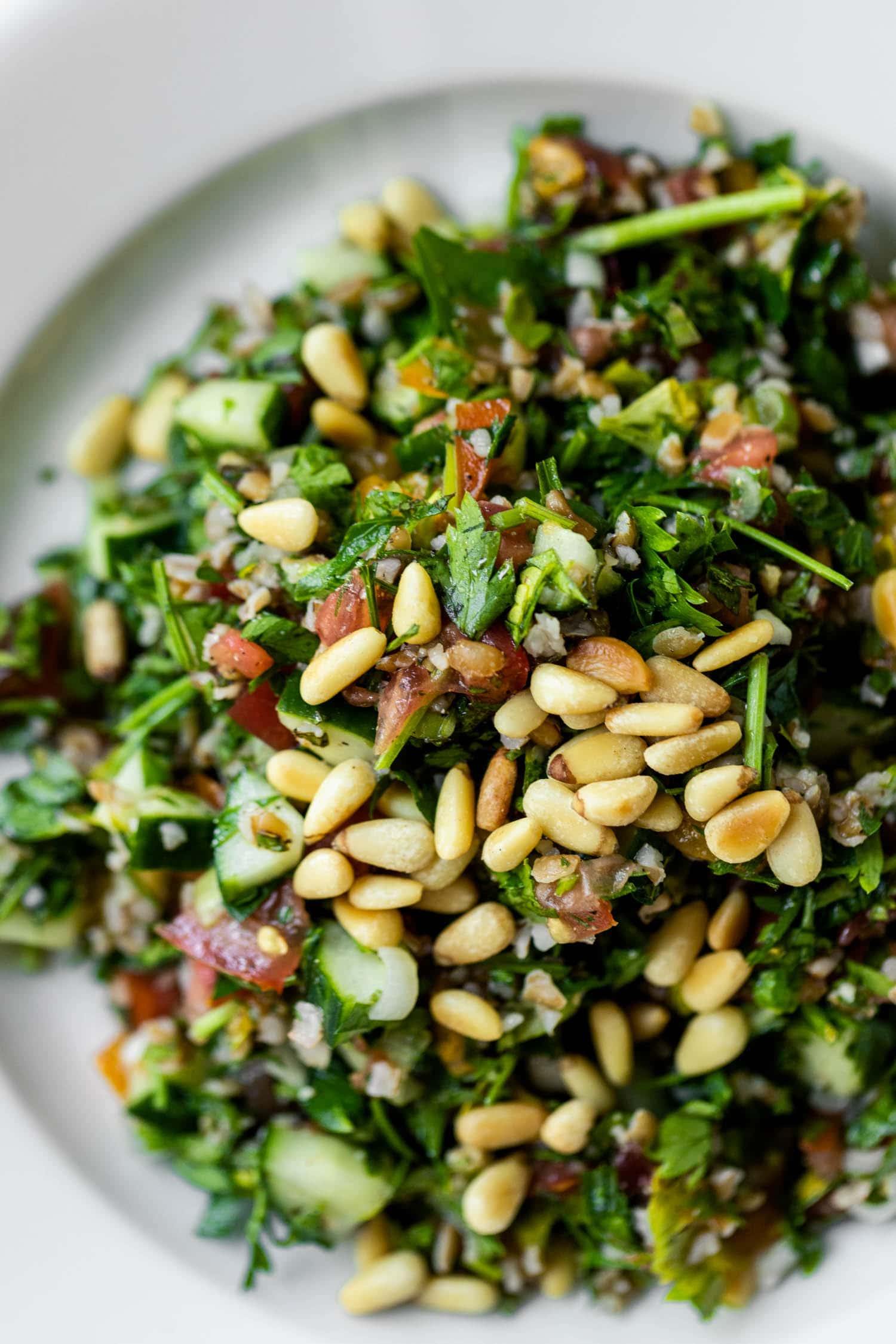 Close up view of bowl full of tabbouleh with pine nuts sprinkled on top
