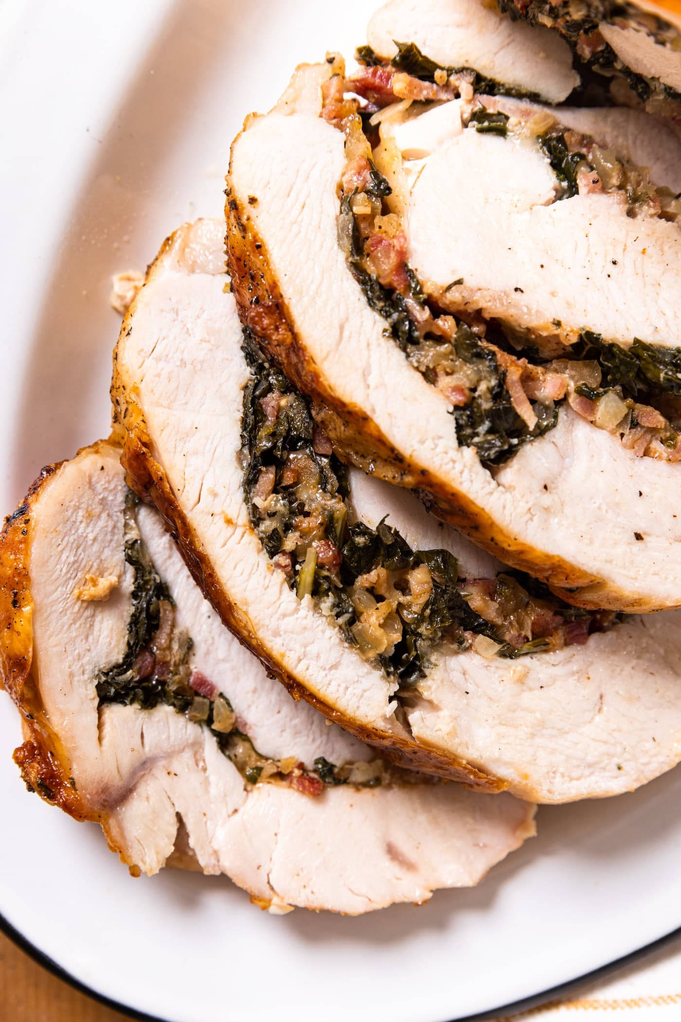 Close up top down view of slices of turkey roulade with bacon and kale stuffing in middle of layers
