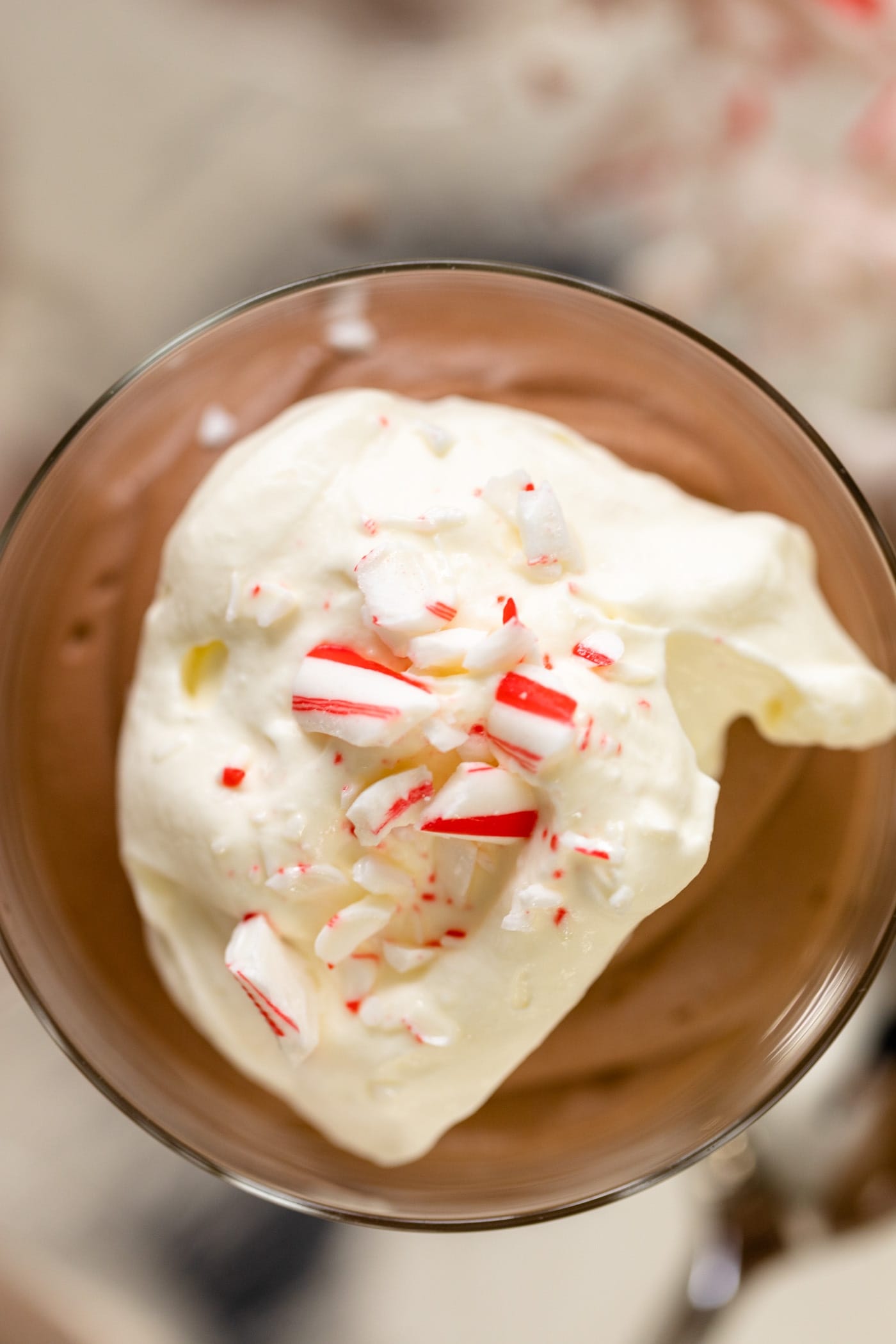Top down view of chocolate mousse sitting in glass topped with whipped cream and peppermint bits all on a silver tray.