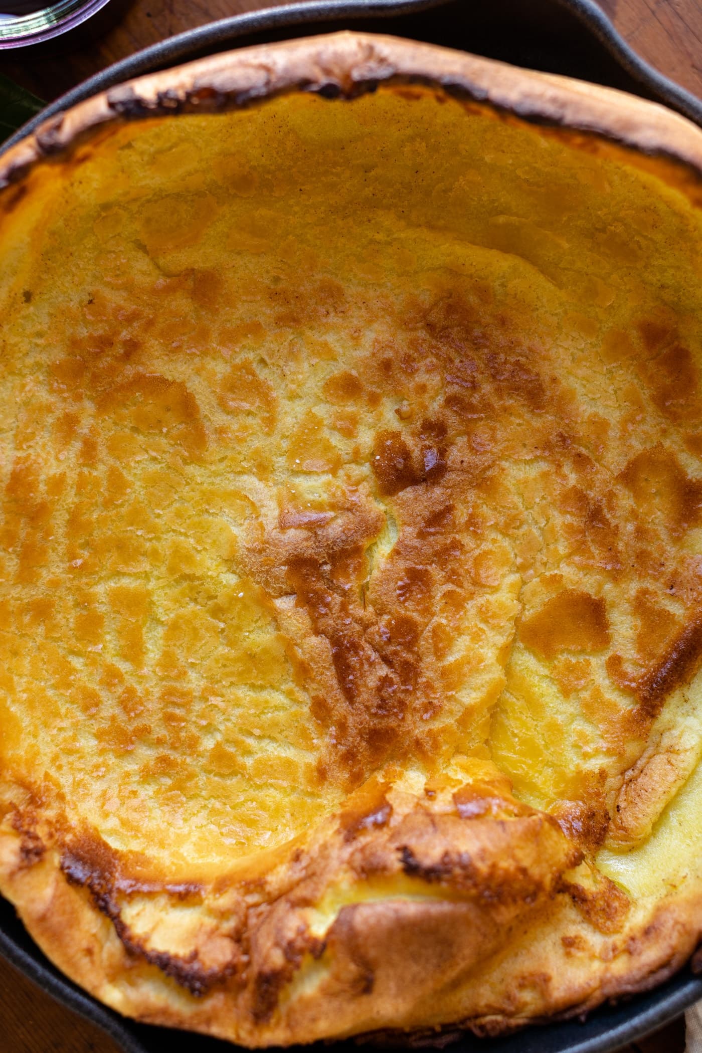 Top down view of citrus Dutch baby in a red skillet on wood surface