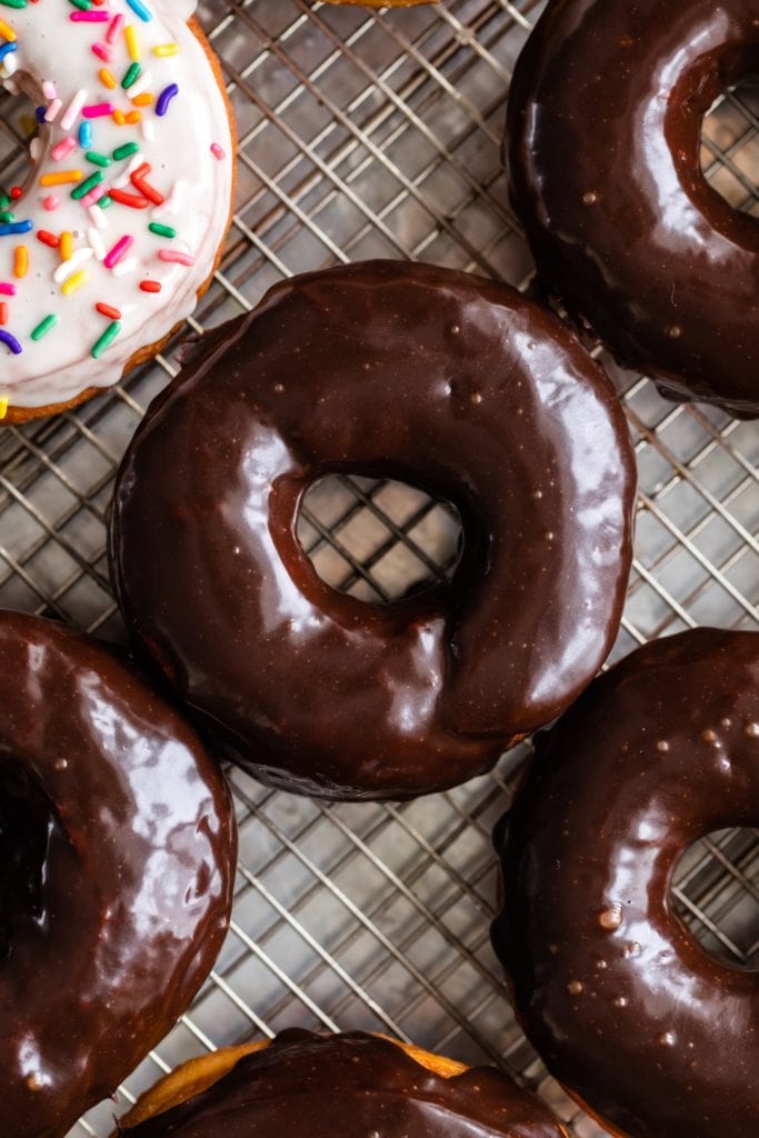 Top down view of homemade yeast donuts topped with chocolate glaze sitting on wire cooling rack