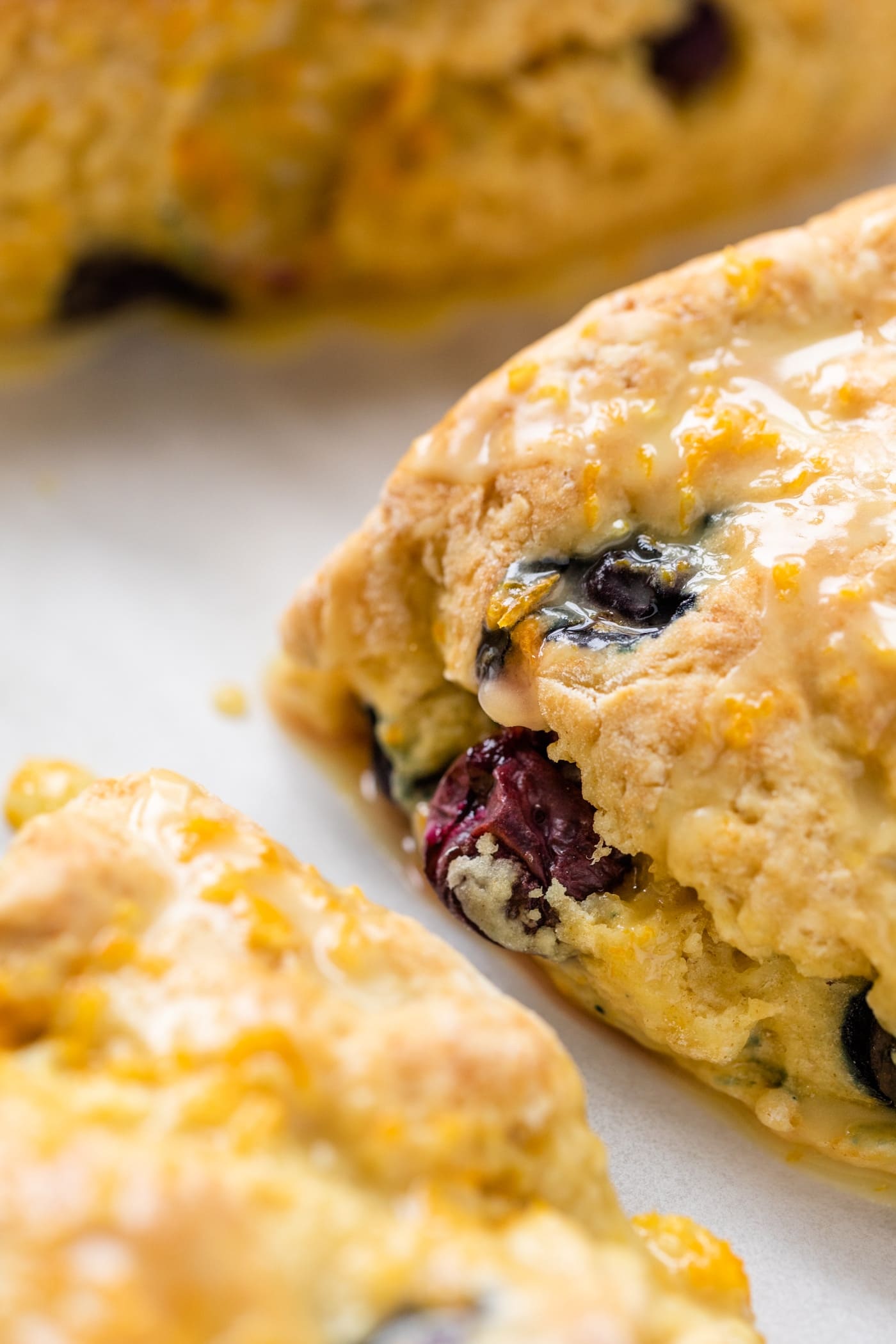 Close up view of side of Irish soda bread scone sitting on piece of parchment with extra scones around