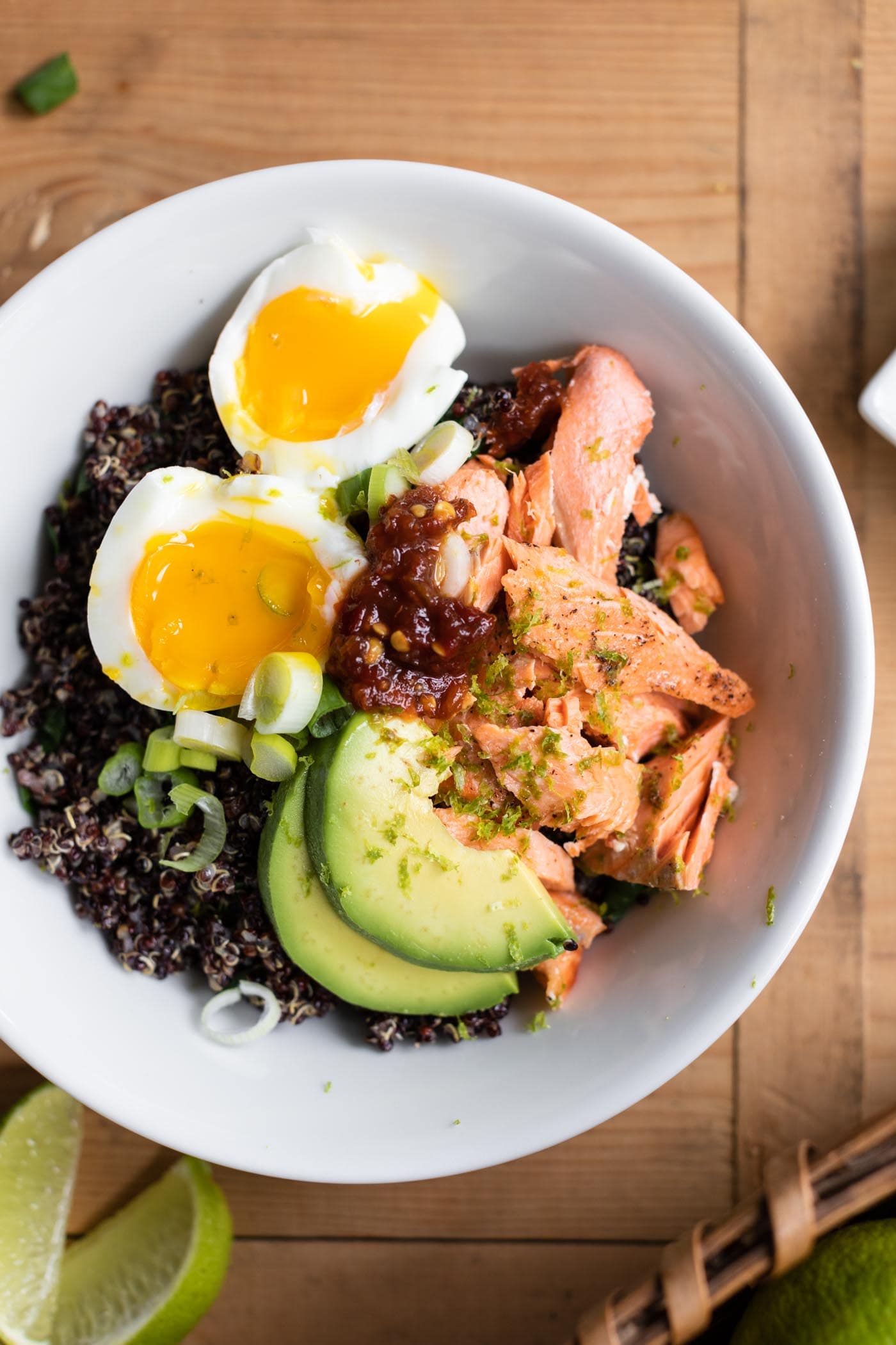 Top down view of salmon bowl topped with sliced egg and avocado all on wood surface