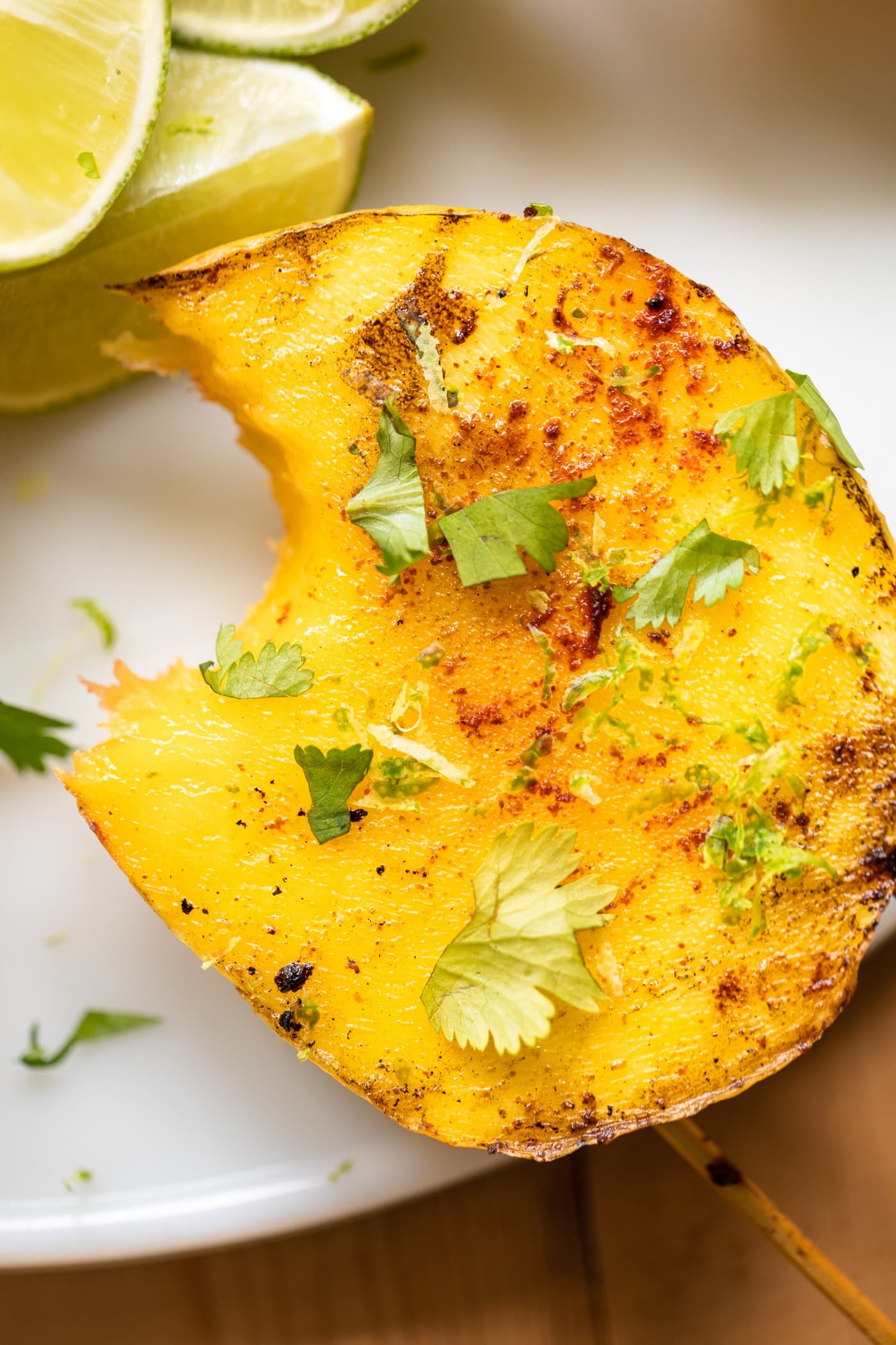 Mango sitting on white serving platter with bite taken out and topped with cilantro and spices