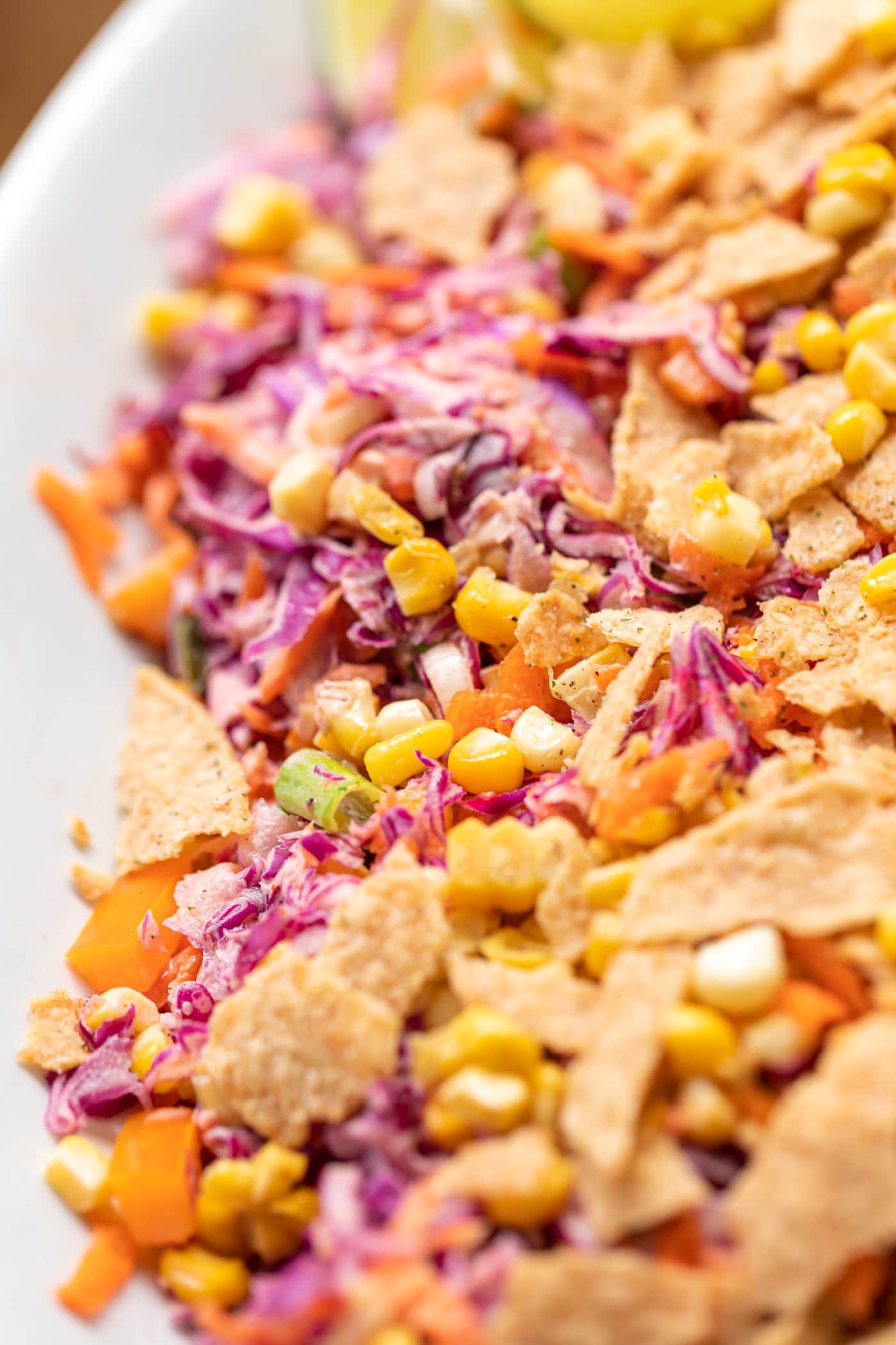 Coleslaw created from red cabbage served with corn and tortilla chips on white serving platter