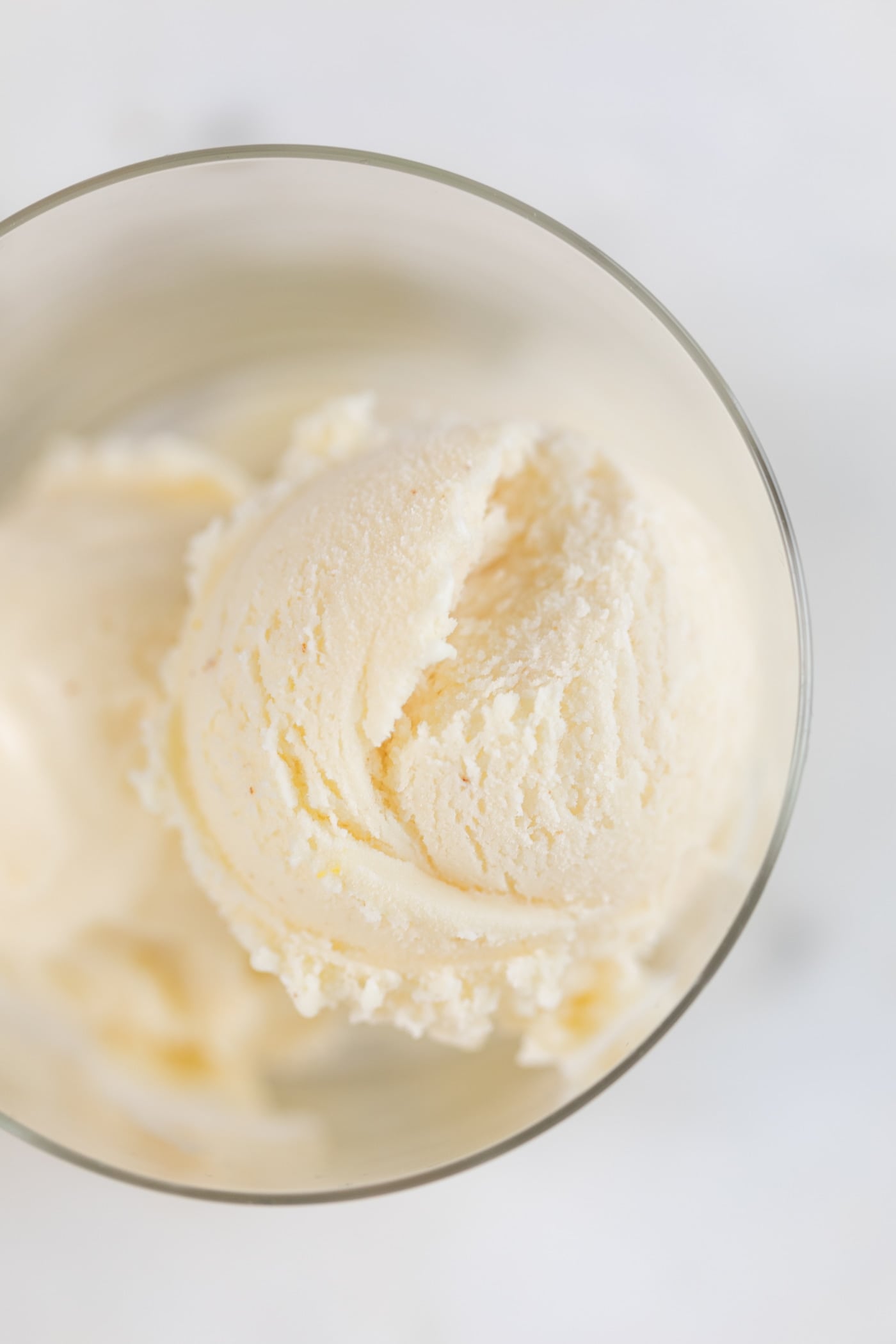 Top down view of orange sage ice cream sitting in glass container on marble surface