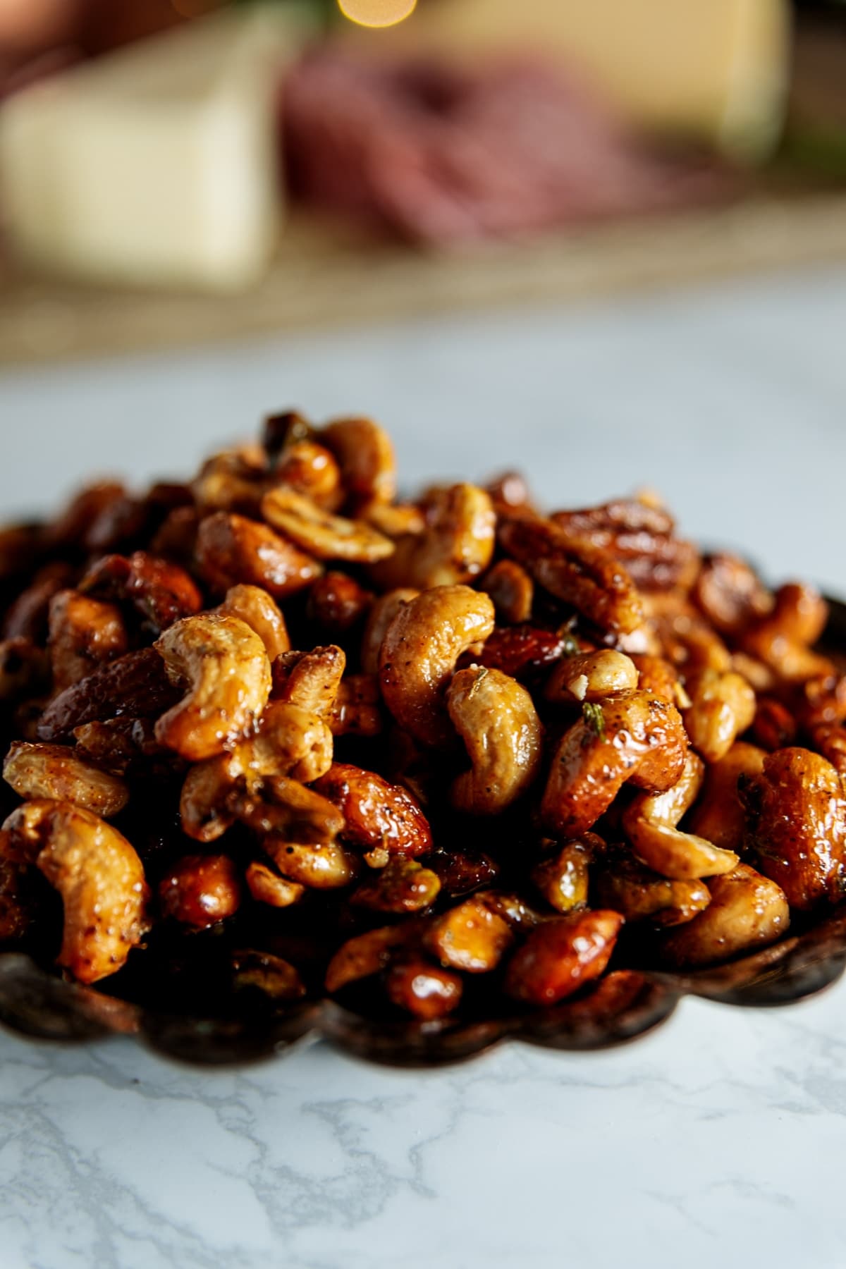 Silver tray filled with candied cajun nuts with tacky surface showing sugary coating all on white marble surface.