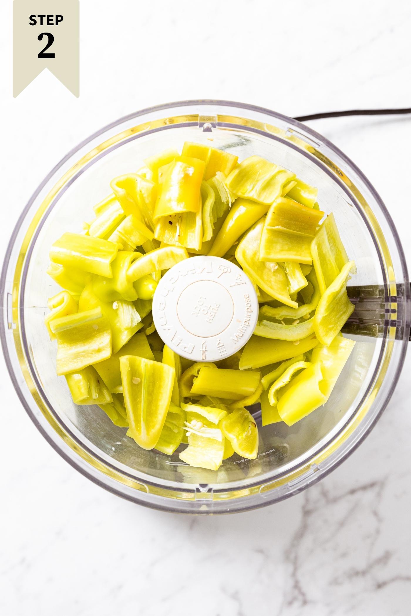 Food processor container filled with roughly chopped hot peppers.