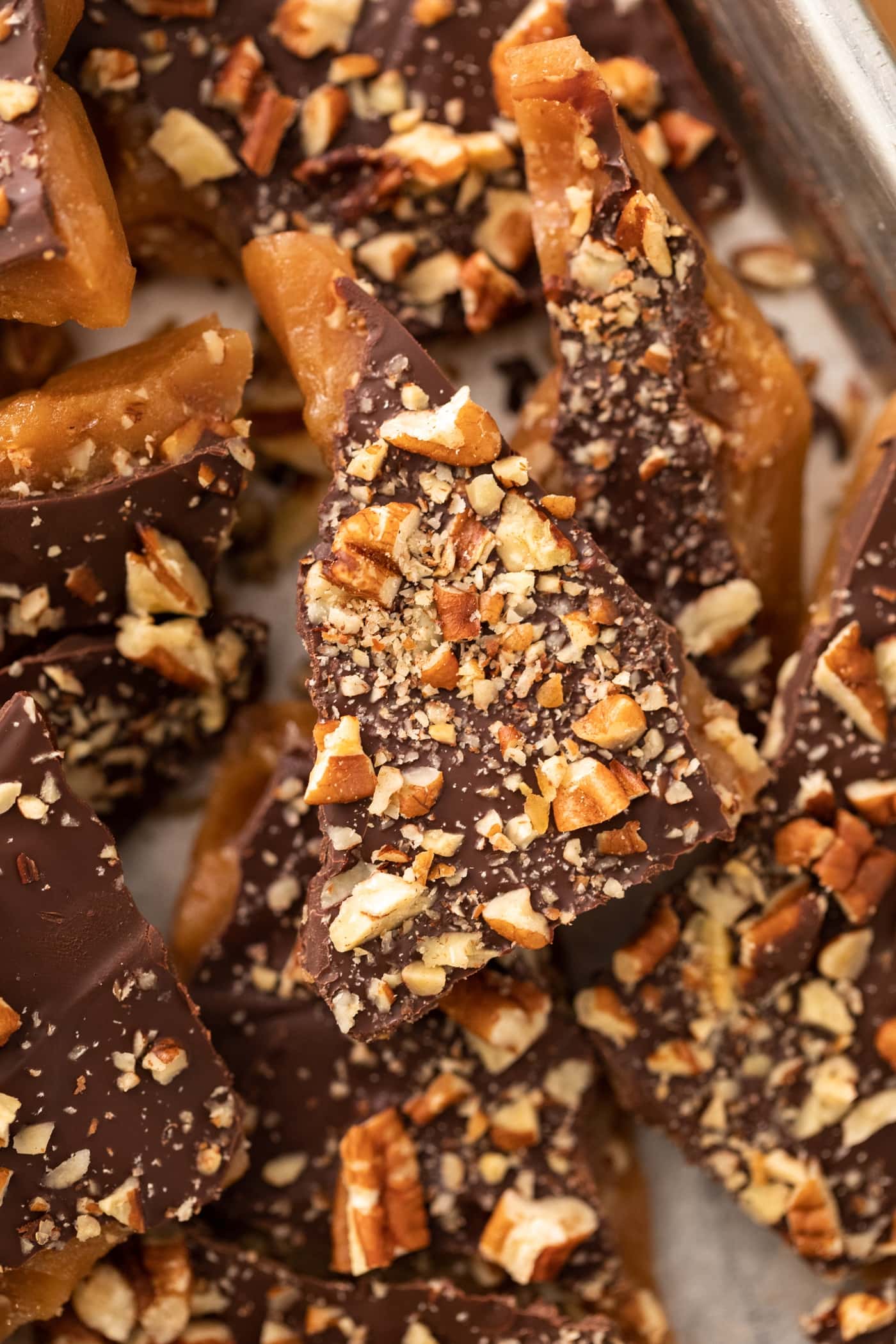 Top down view of English toffee sitting on top of other pieces of toffee all in a silver baking pan