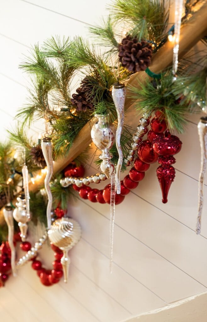 Red and silver garland and ornaments hanging from a wood banister in stairway