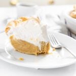 White plate with piece of brown colored butterscotch pie with creme brûlée topping with fork and rest of pie in background