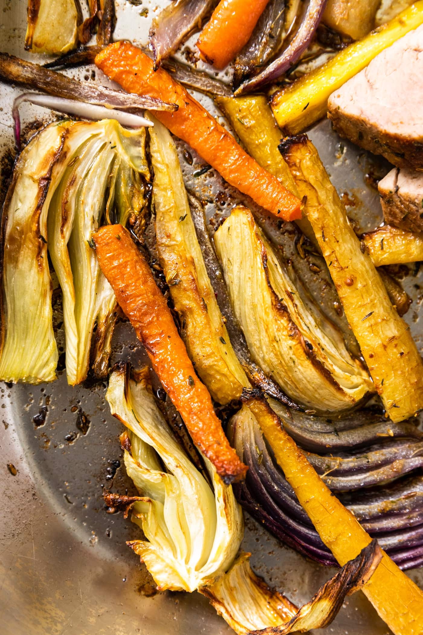 Top down view of roasted carrots and slices of fennel bulb sitting in roasting pan