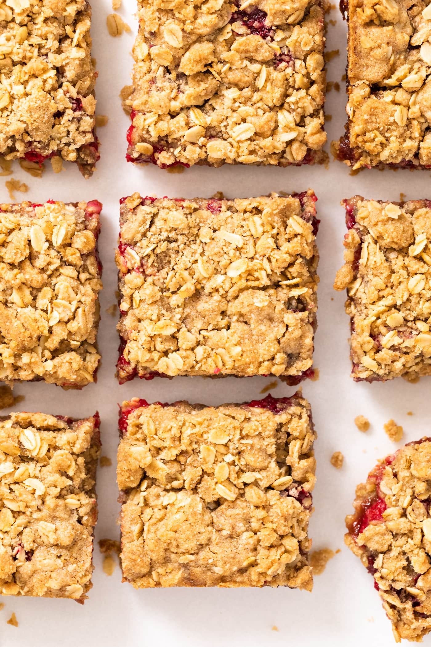 Top down view of square pieces of golden colored crumb bars with a red raspberry filling peeking out