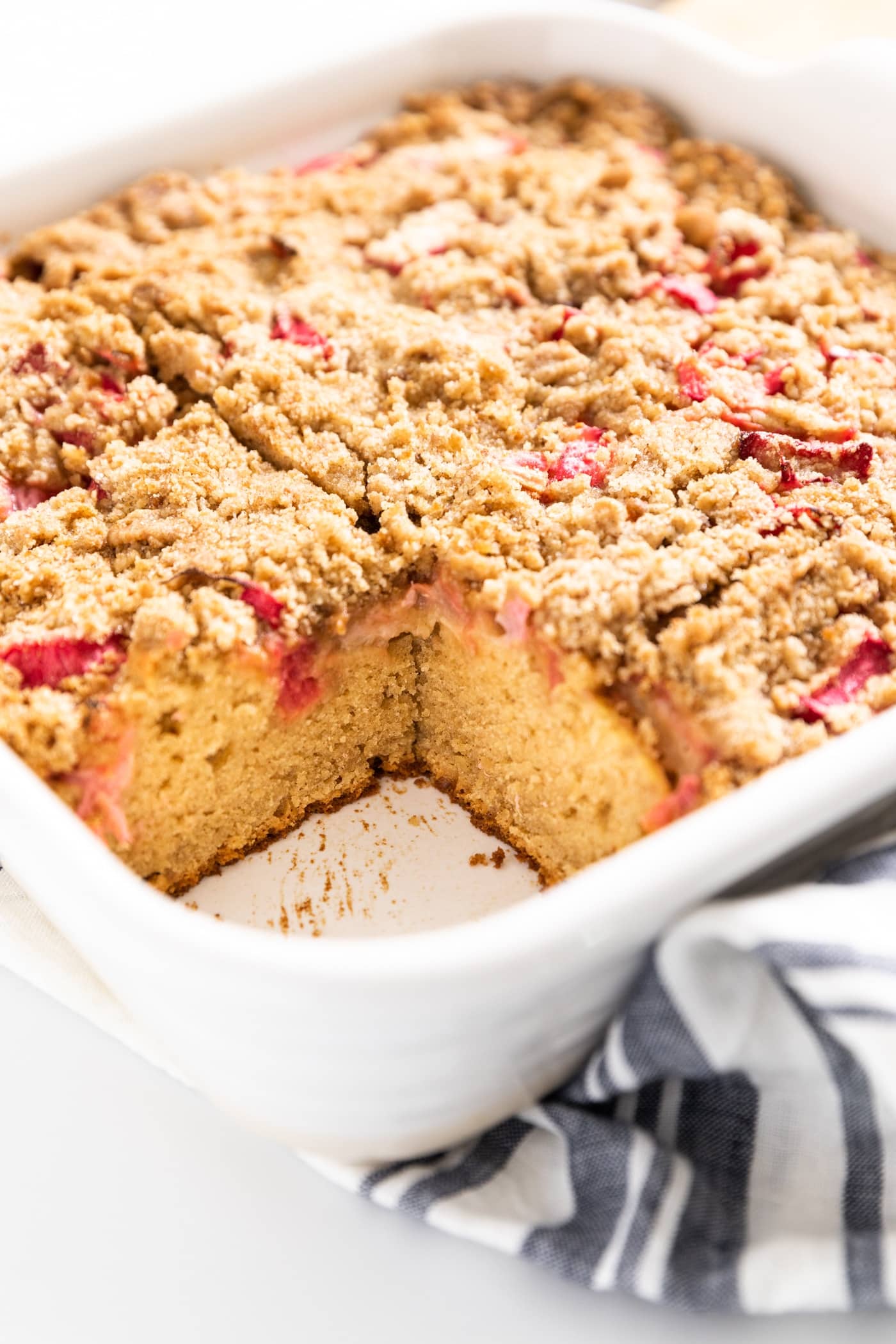 Close up view of interior of coffee cake with pieces of rhubarb within all on white surface