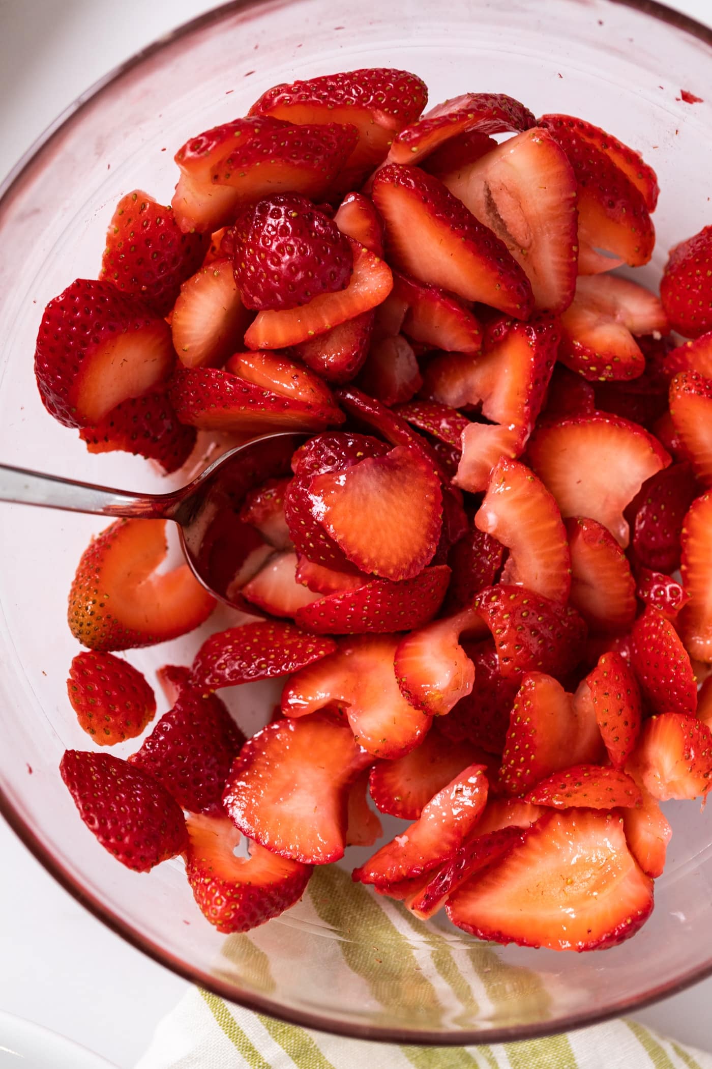 Top down view of macerated strawberries sitting glass bowl with spoon