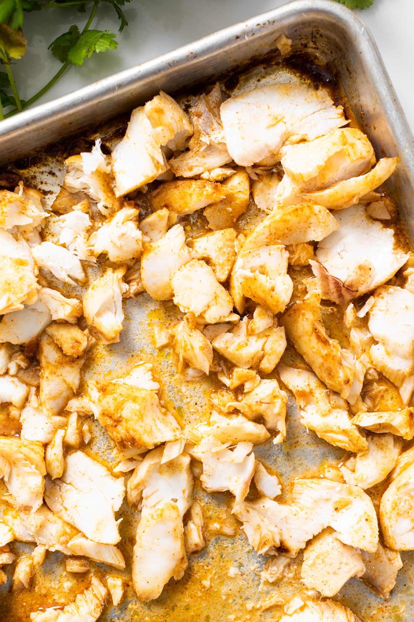 Top down view of shredded cod after being roasted in oven and topped with spices