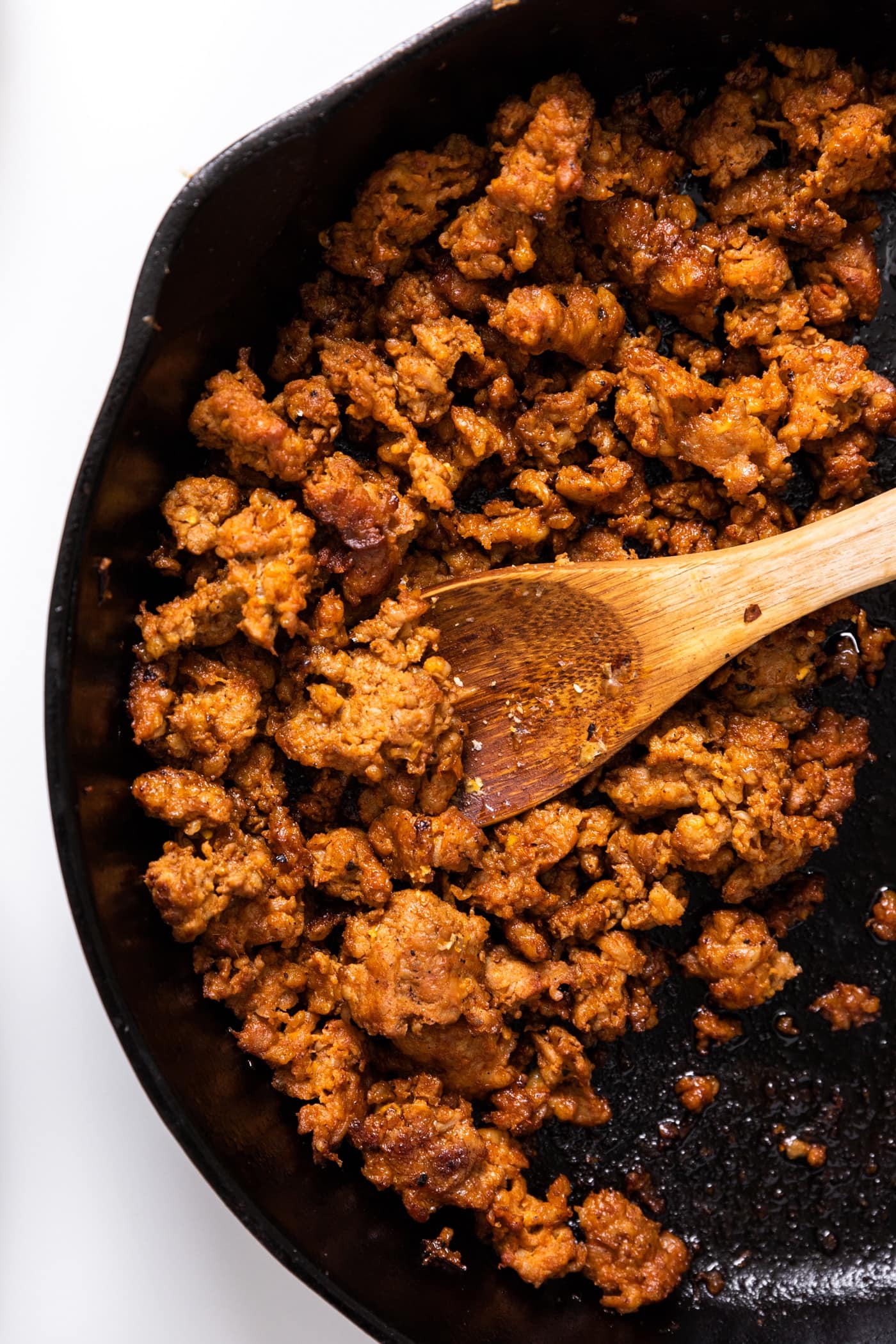 Top down view of cooked brown colored chorizo meat sitting in cast iron skillet sitting on white countertop