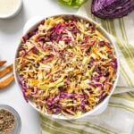 Top down view of white bowl with green striped cloth underneath filled with green and purple colored cabbage