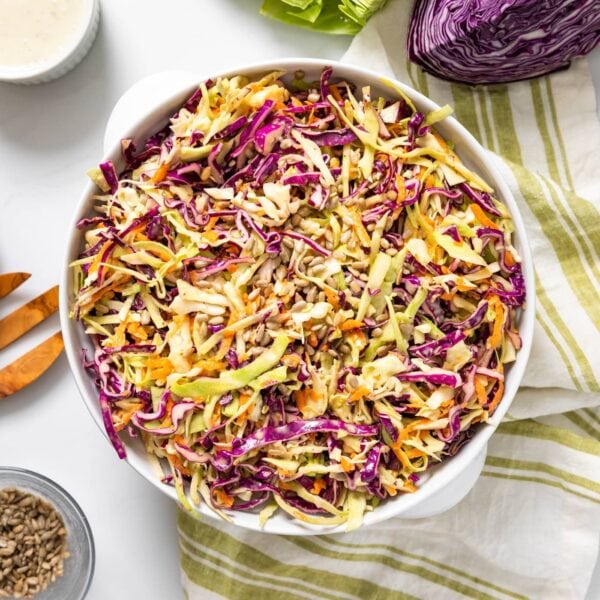 Top down view of white bowl with green striped cloth underneath filled with green and purple colored cabbage