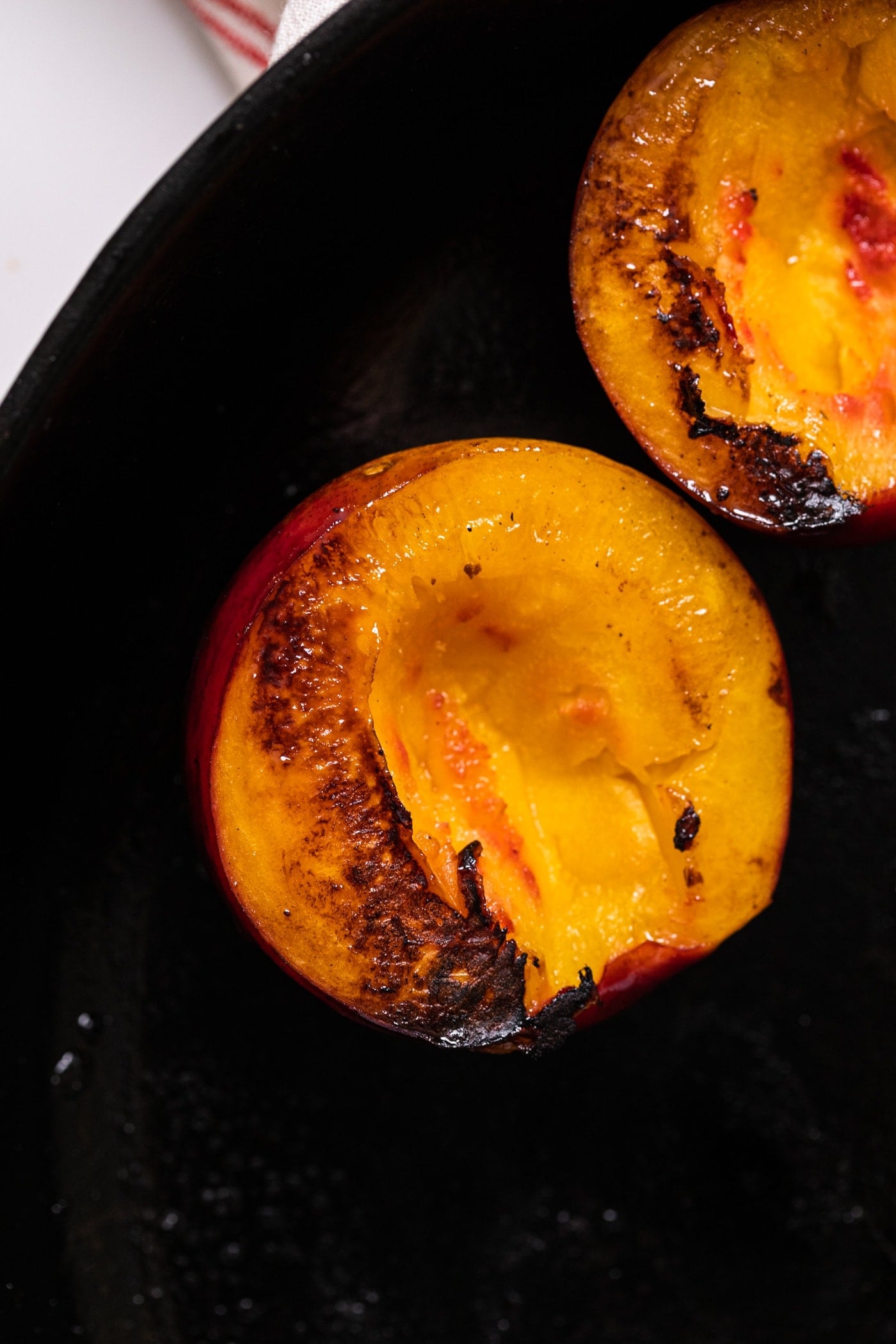 Top down view of grilled nectarine sitting in black cast iron skillet