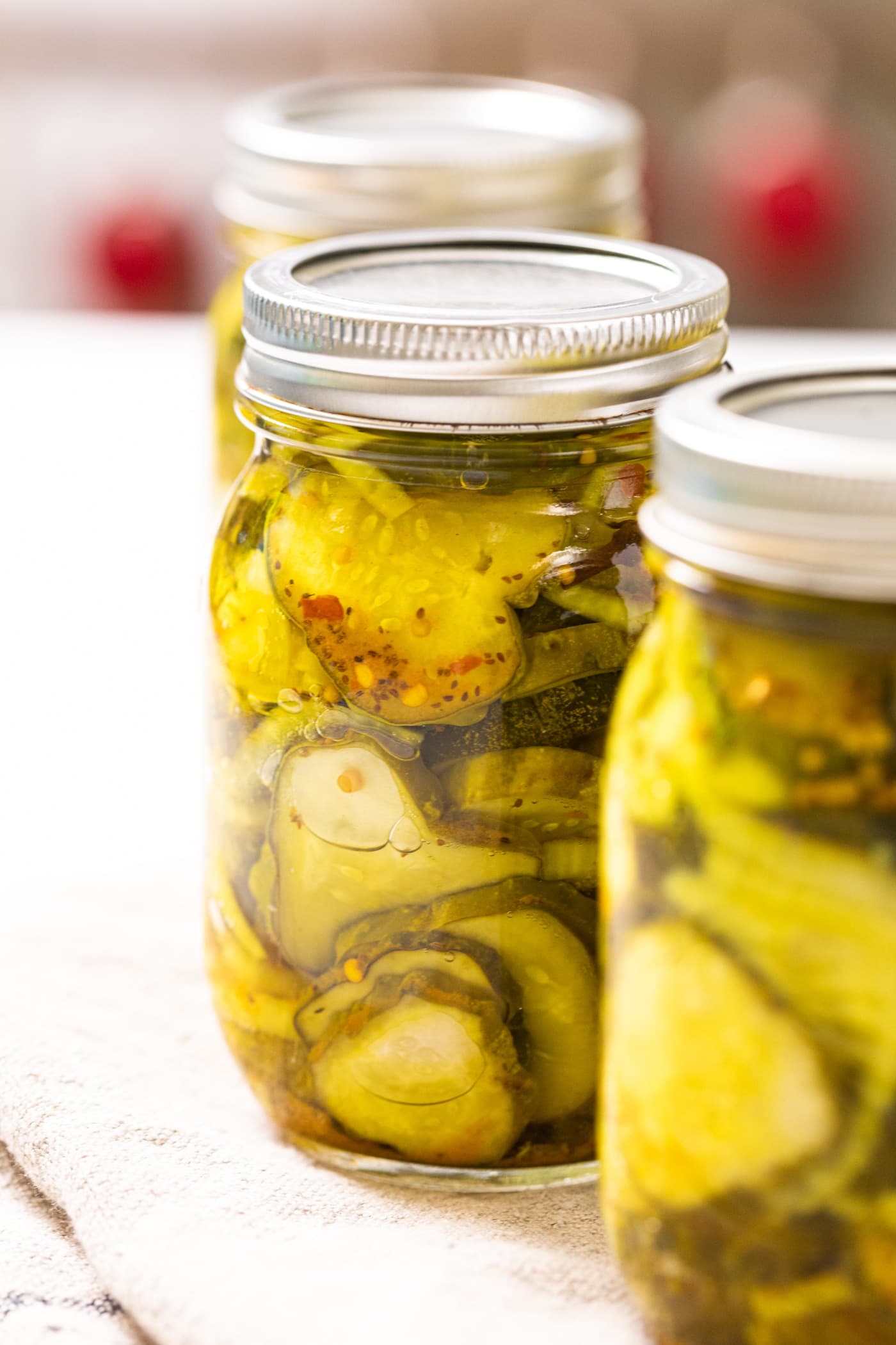 Glass canning jar filled with slices of green and yellow pickles in brining liquid