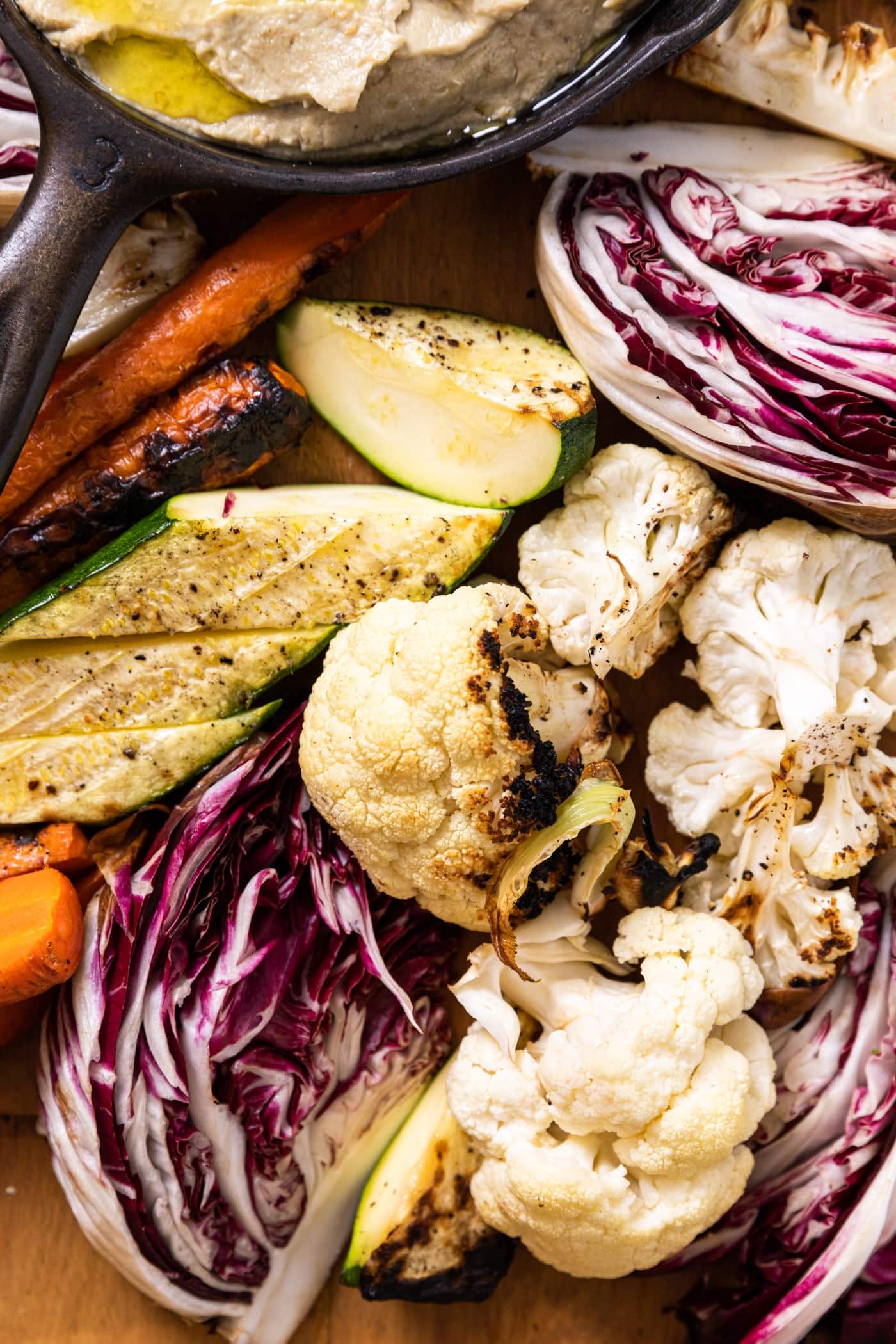 Assortment of grilled vegetables including zucchini, cauliflower, and carrots sitting on wood board
