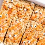 Top down view of white pan holding Rice Krispie treats topped with orange colored white chocolate