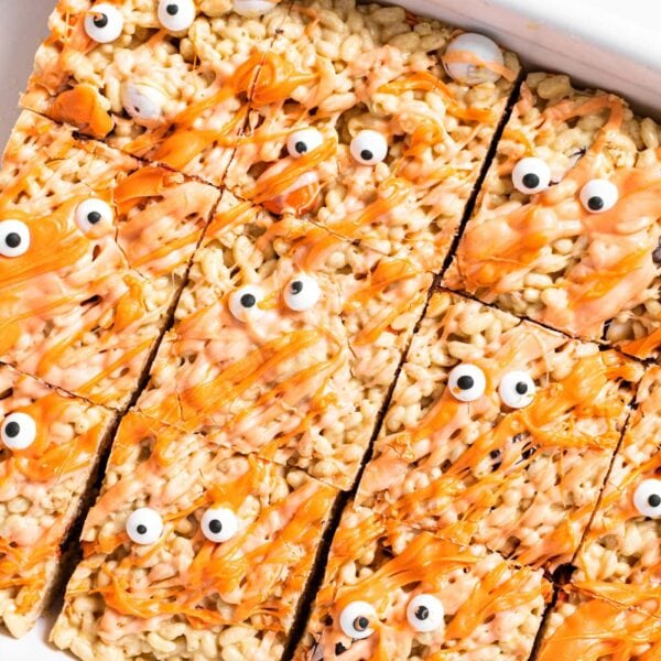 Top down view of white pan holding Rice Krispie treats topped with orange colored white chocolate