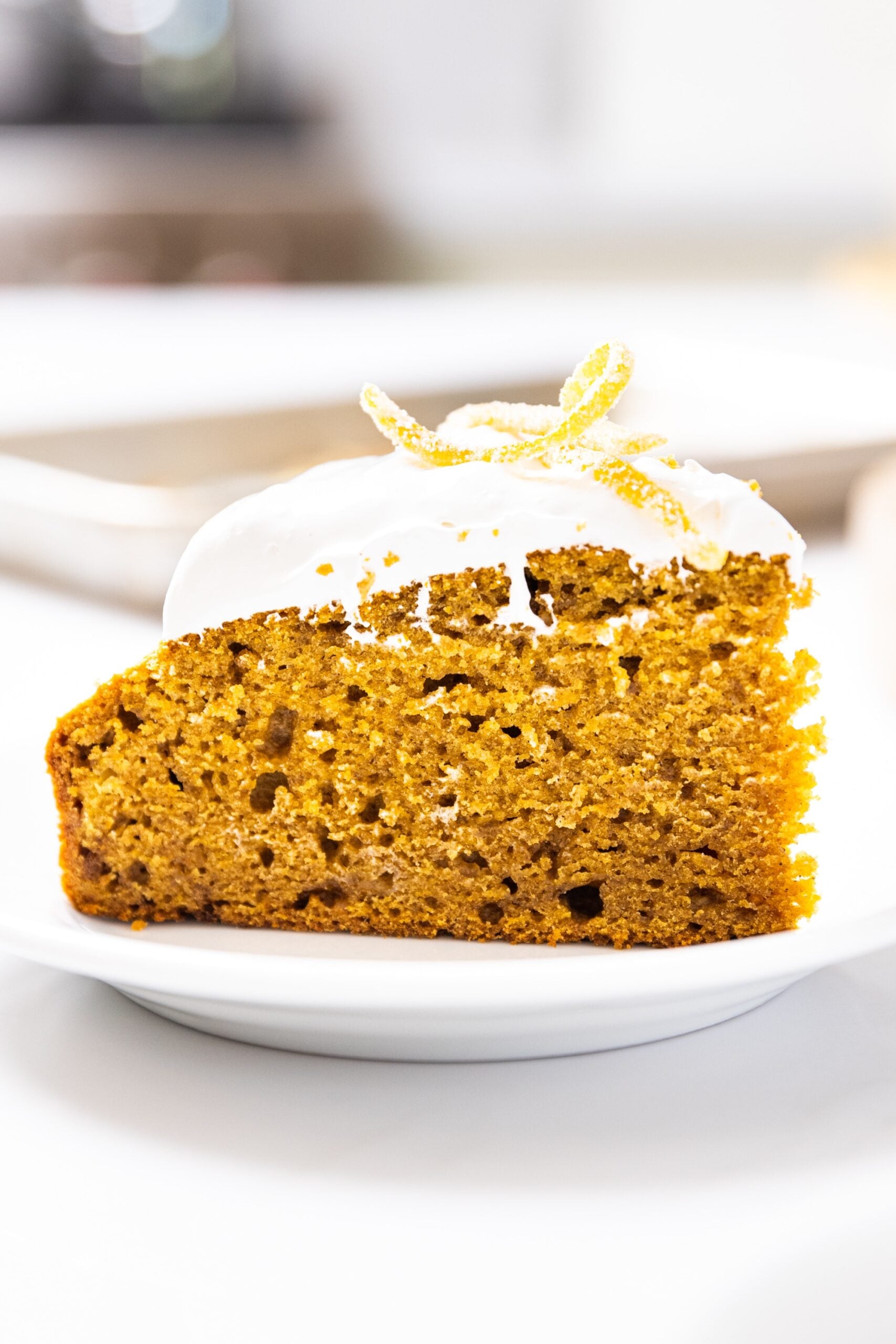 Close up side view of pumpkin applesauce cake topped with whipped topping and candied orange zest pieces