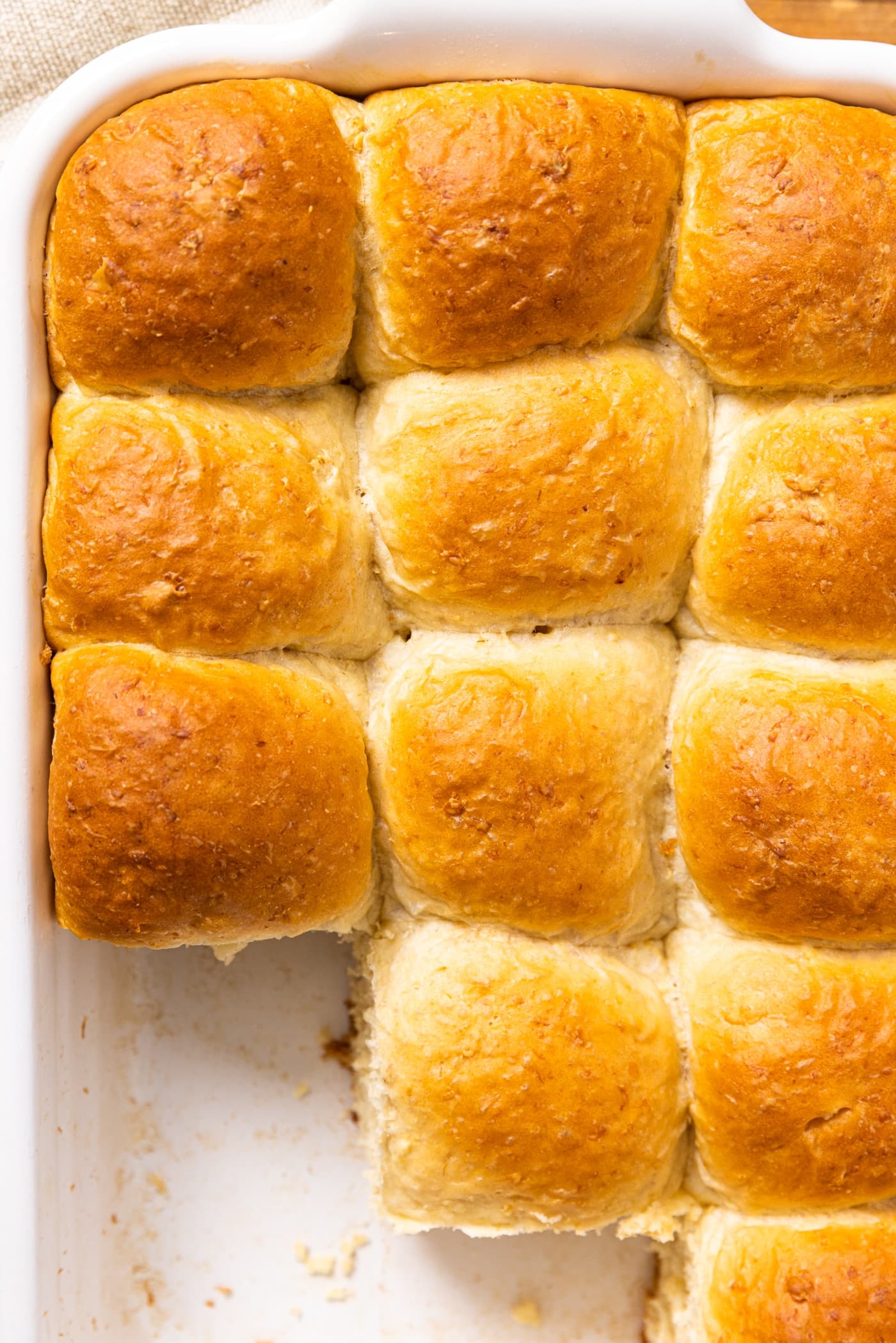 Top down view of white baking dish filled with golden brown dinner rolls after being taken out of the oven