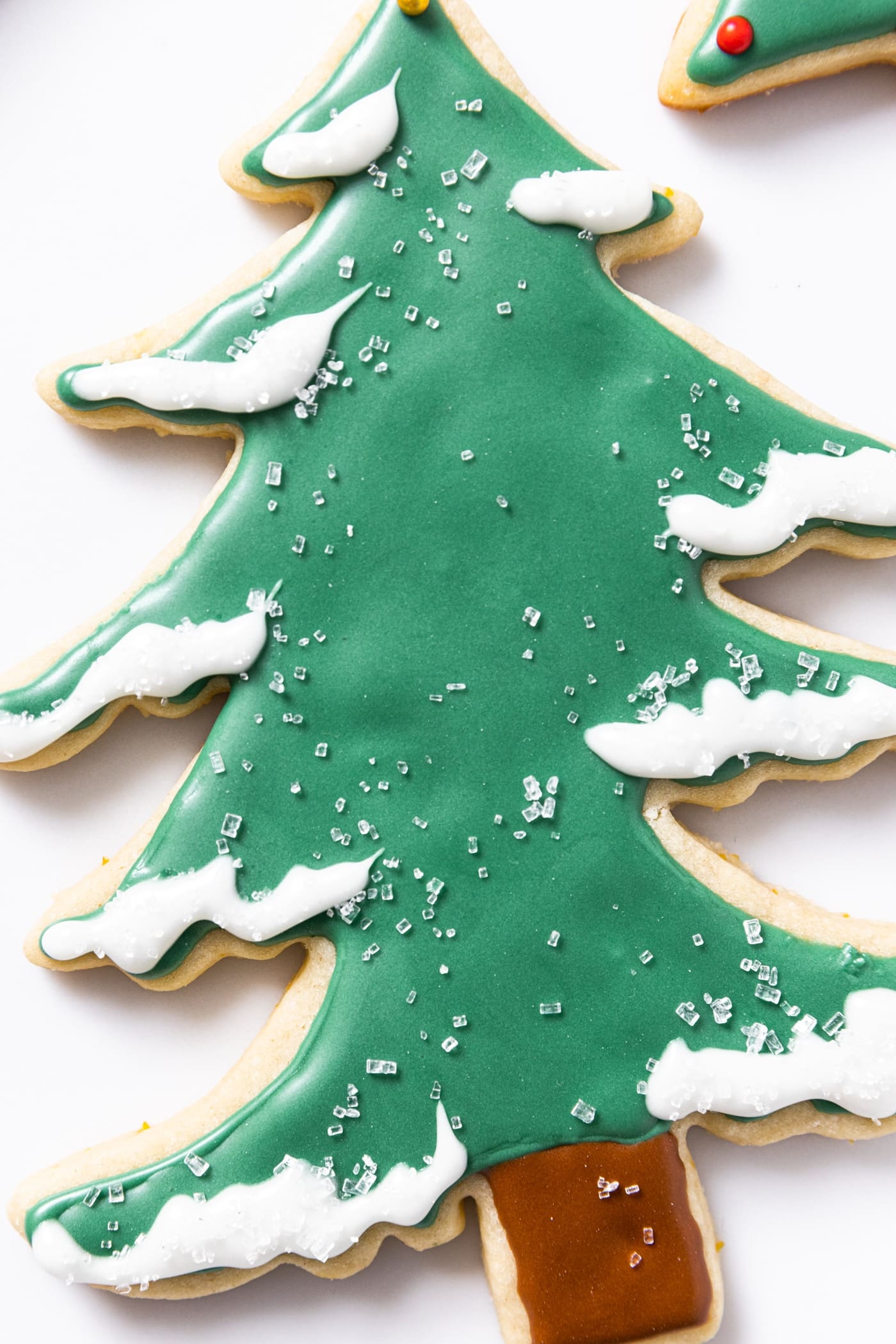 Top down close up view of green colored Christmas tree shaped sugar cookie sitting on white countertop