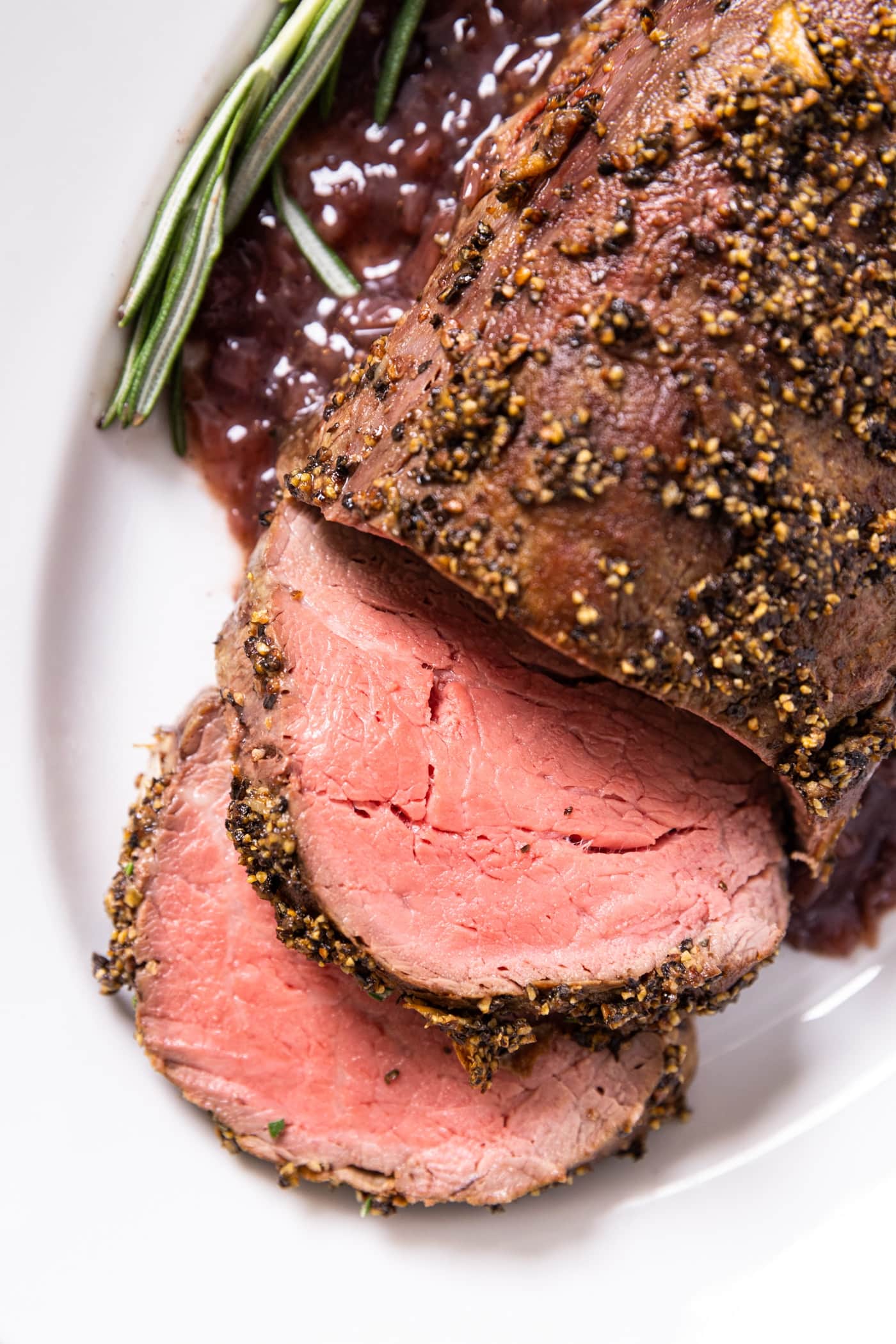 Top down view of white platter filled with beef tenderloin sitting on top with two slices laying over
