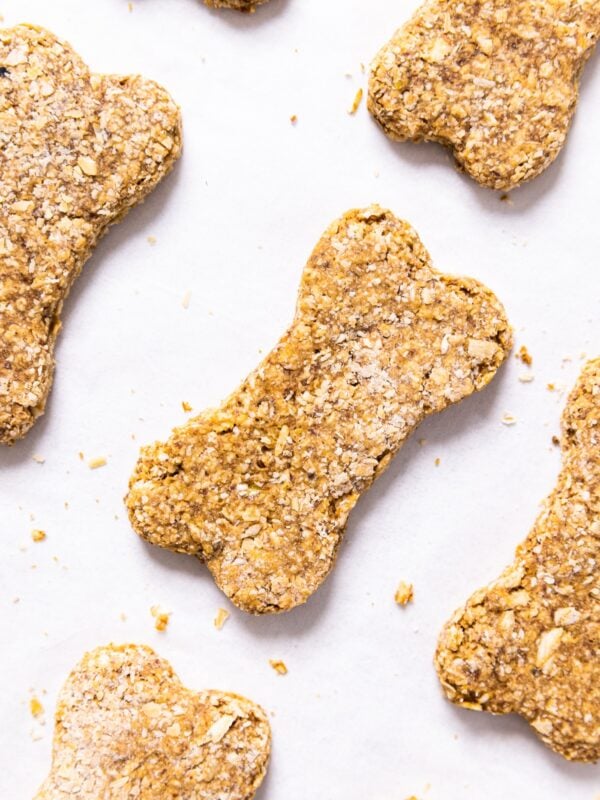 Top down view of white parchment paper with bone-shaped peanut butter dog biscuits