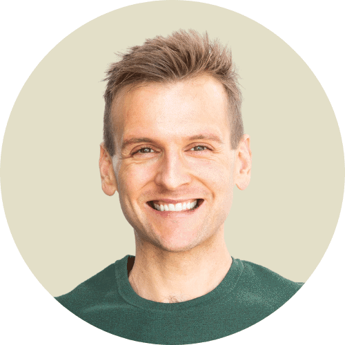 Kaleb Wyse in green sweatshirt standing in front of light tan background