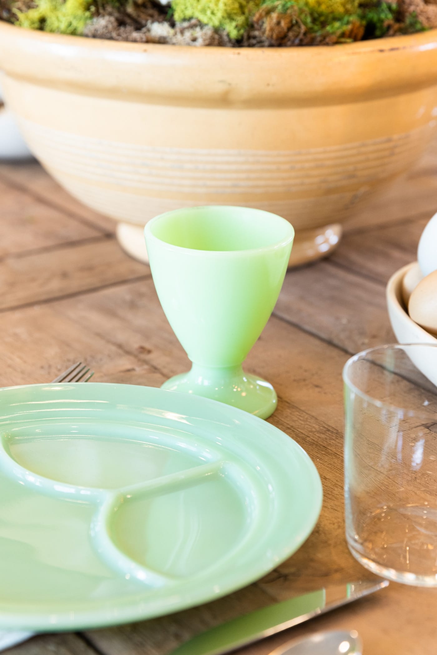 Green jadeite cup sitting in front of jadeite plate on wood dining table