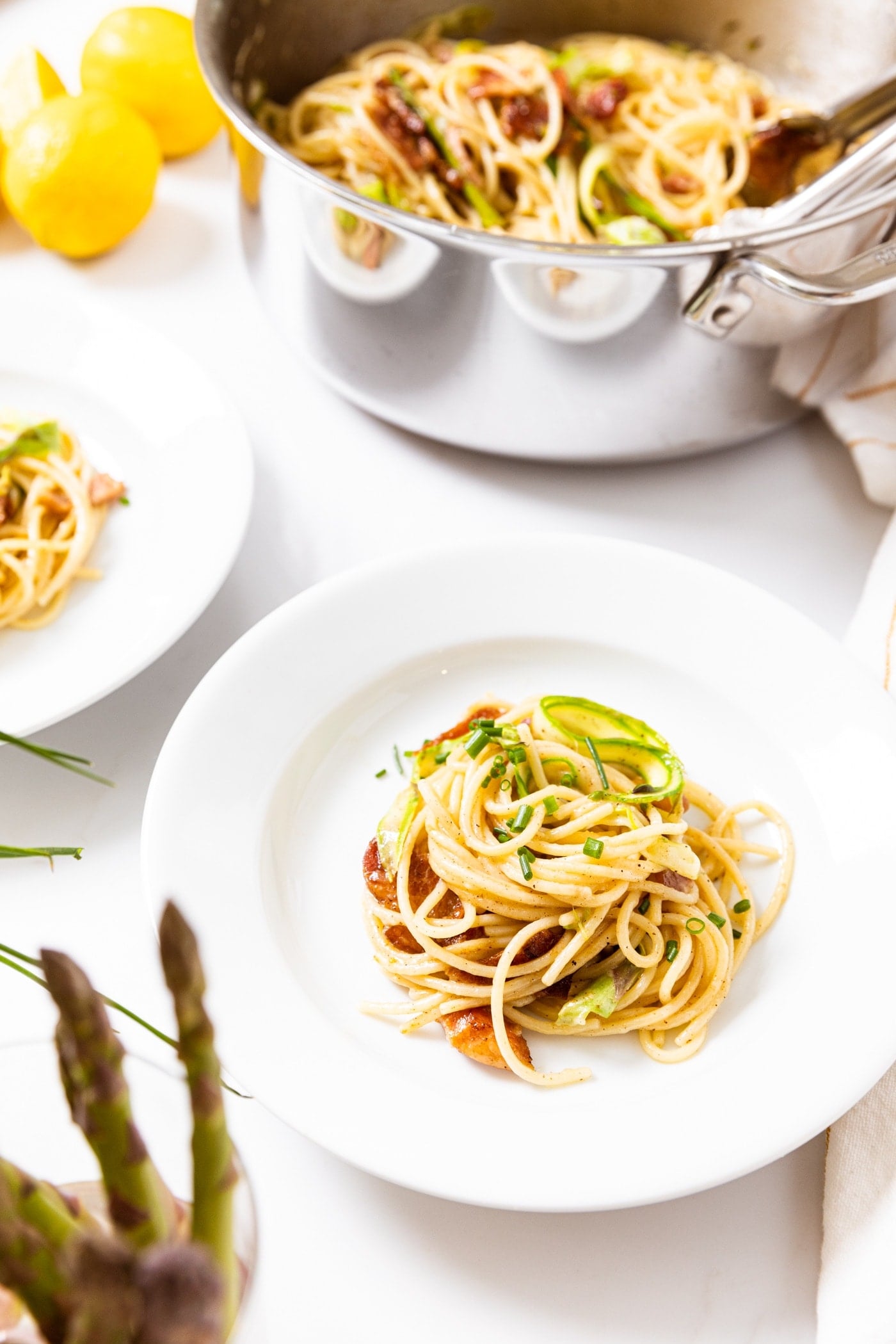 White plate filled with serving of spaghetti with brown butter sauce on top with pot in background filled with more noodles