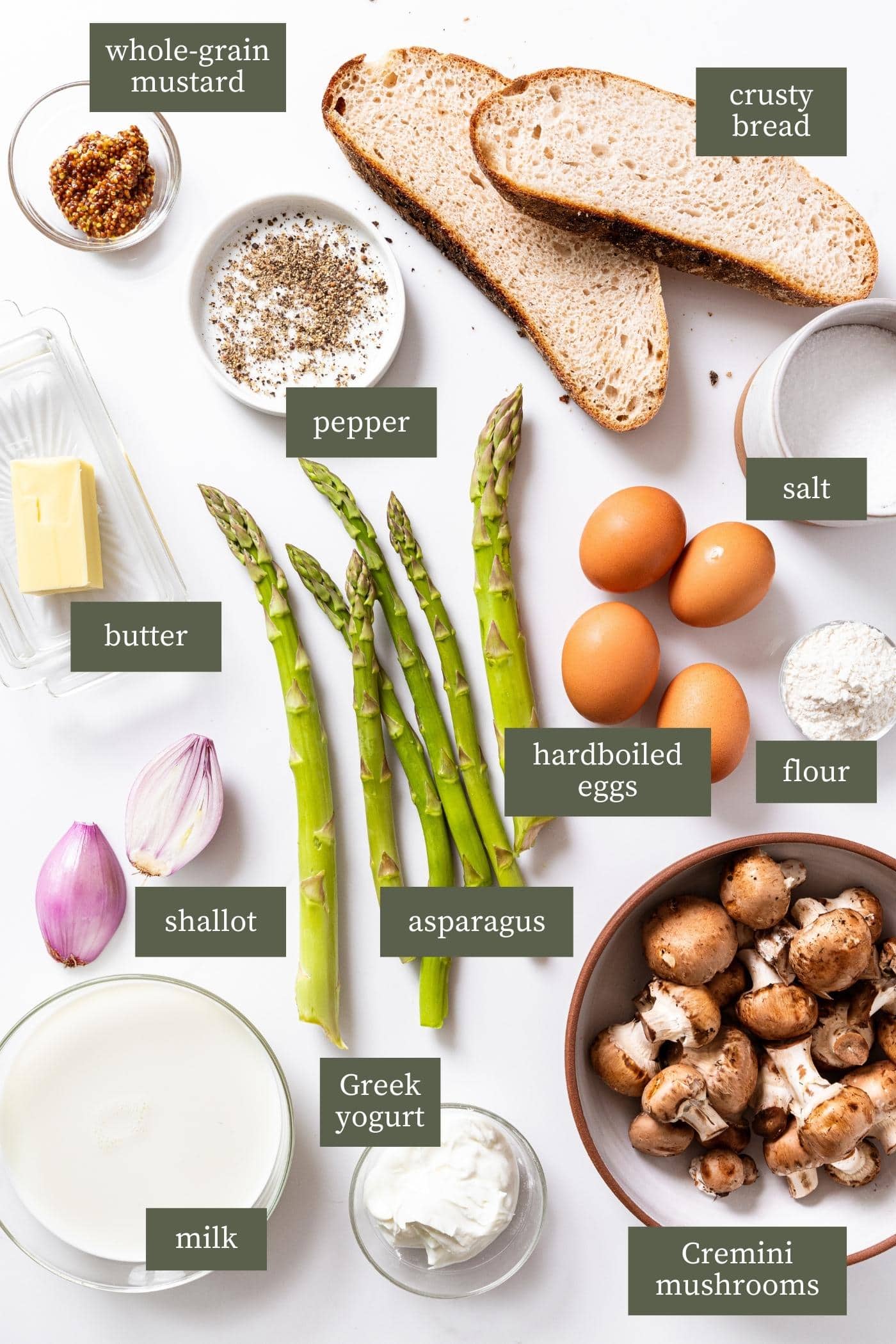 White surface filled with all ingredients to make creamed asparagus including asparagus, bread, mushrooms, milk, and eggs