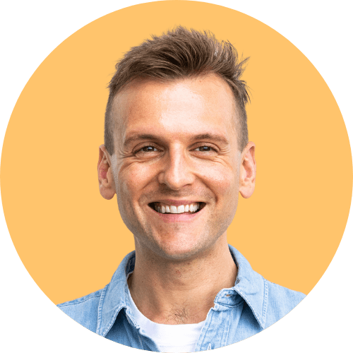 Kaleb Wyse wearing blue colored collared shirt standing in front of orange colored background.