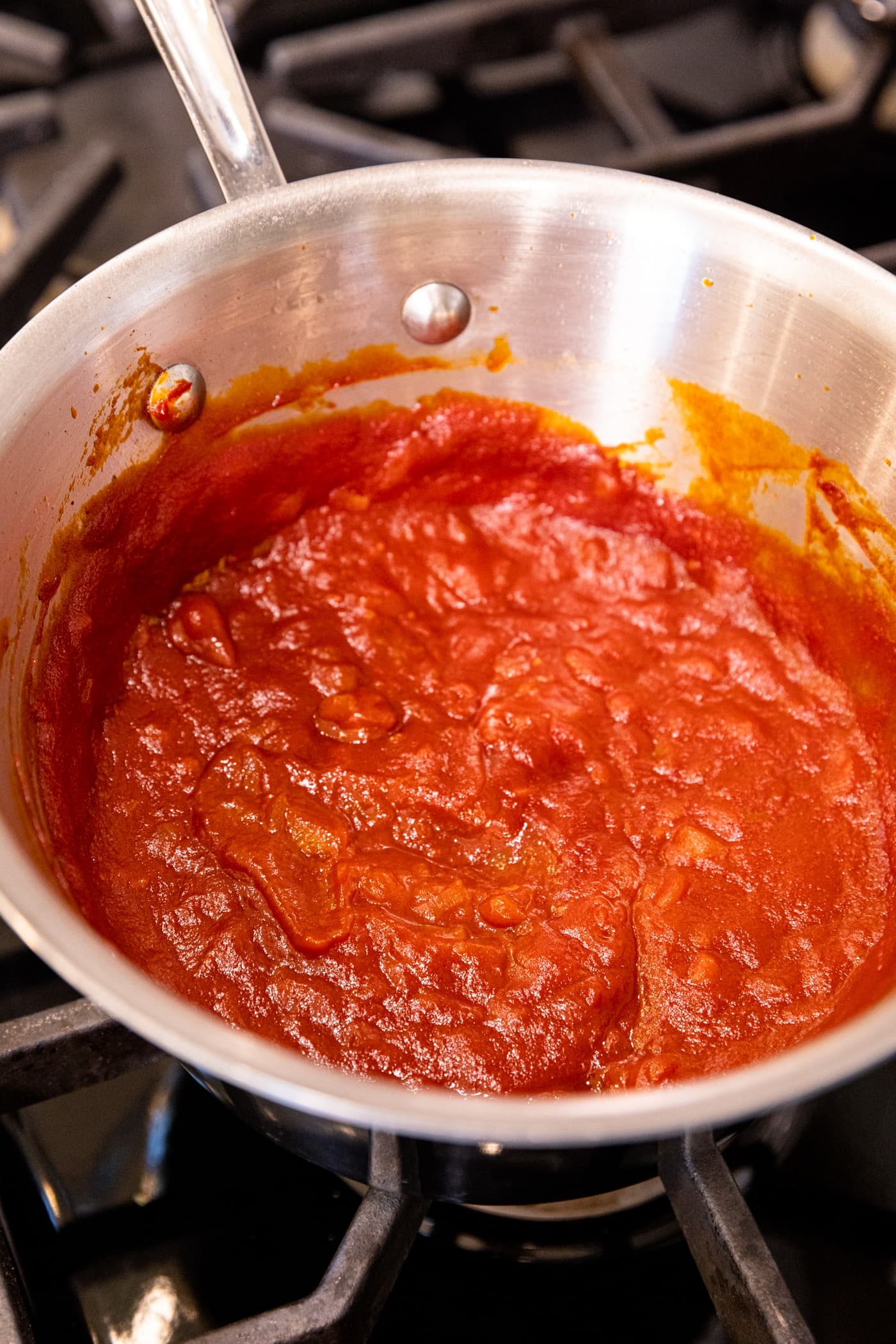 Small metal saucepan filled with cooked barbecue sauce that's red in color.