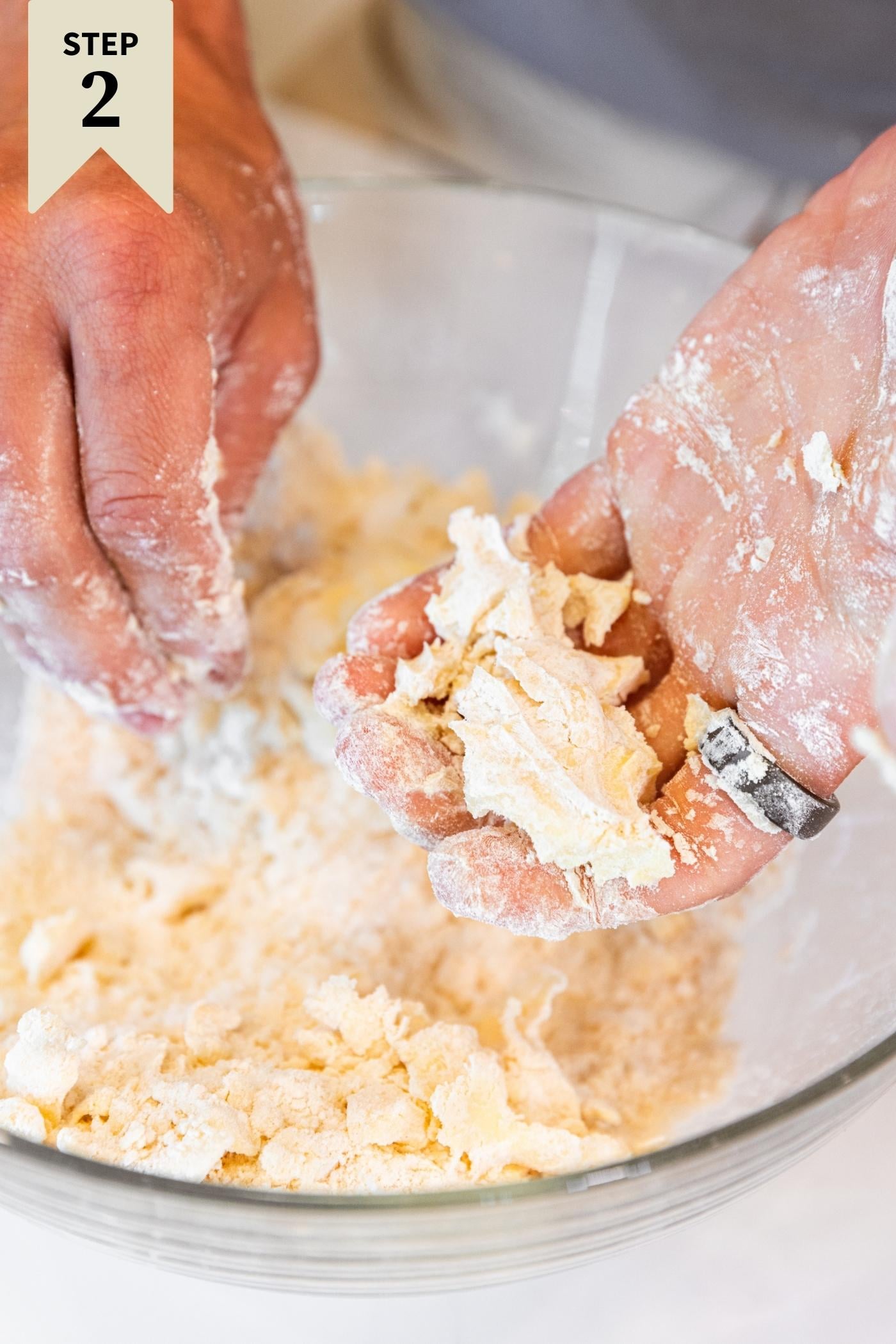 Hand showing dough compacted after making a fist with glass bowl below.