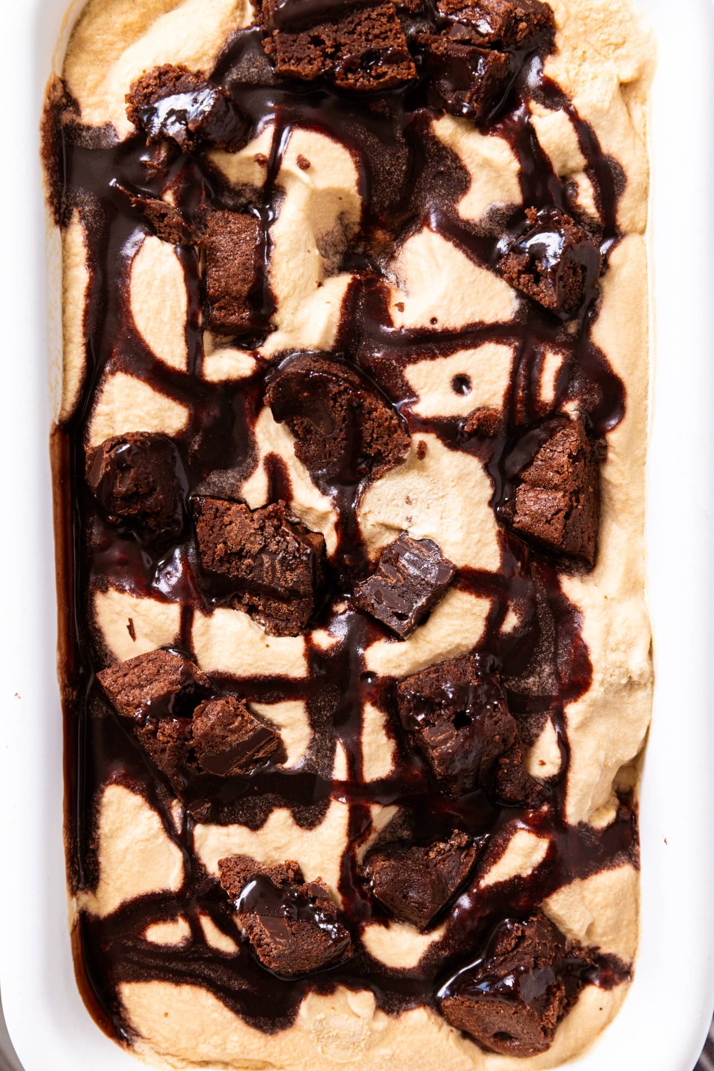 Espresso brownie ice cream drizzled with chocolate sauce sitting in white pan.