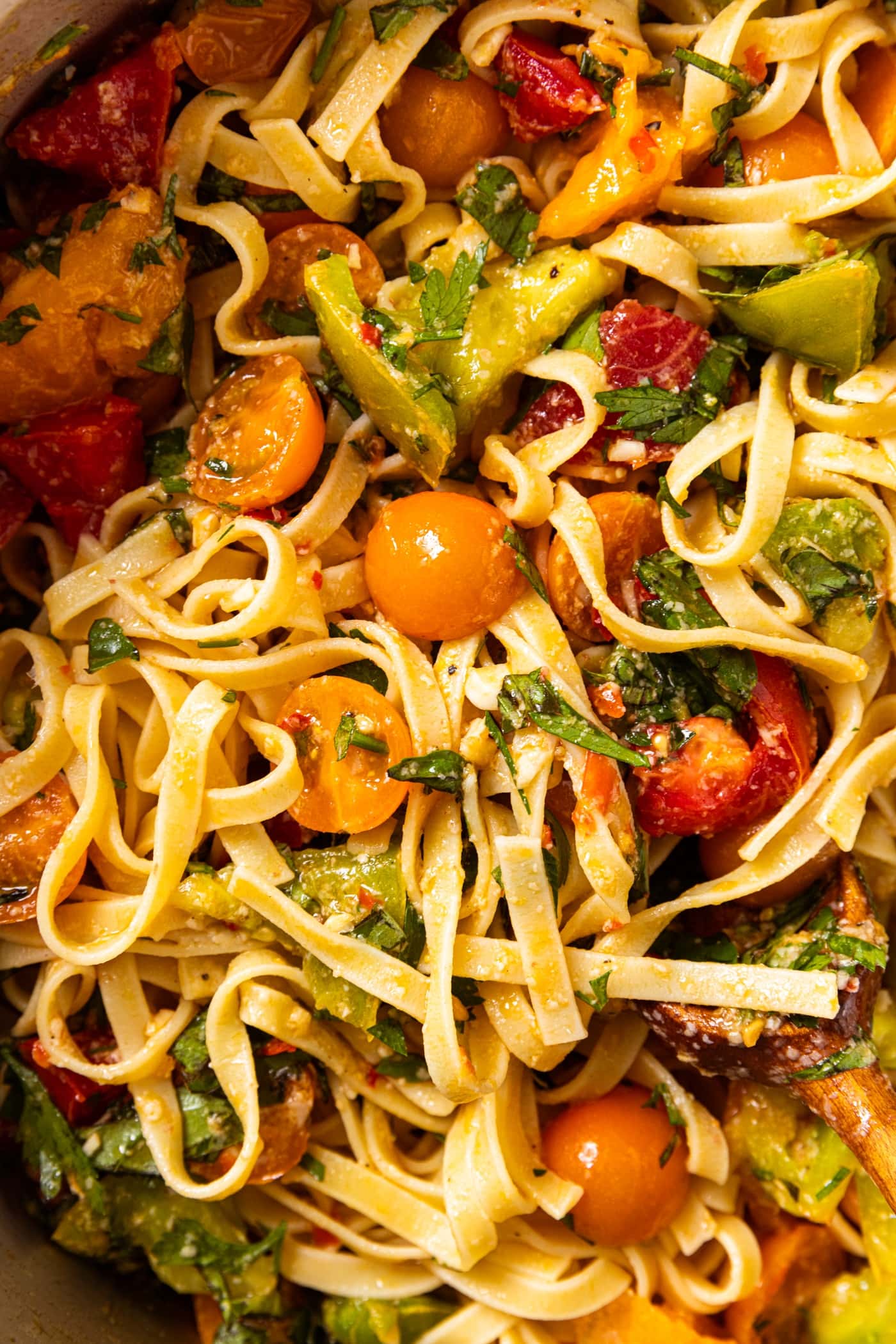 Pot filled with pasta, tomatoes, and herbs, all mixed together and topped with Parmesan cheese.