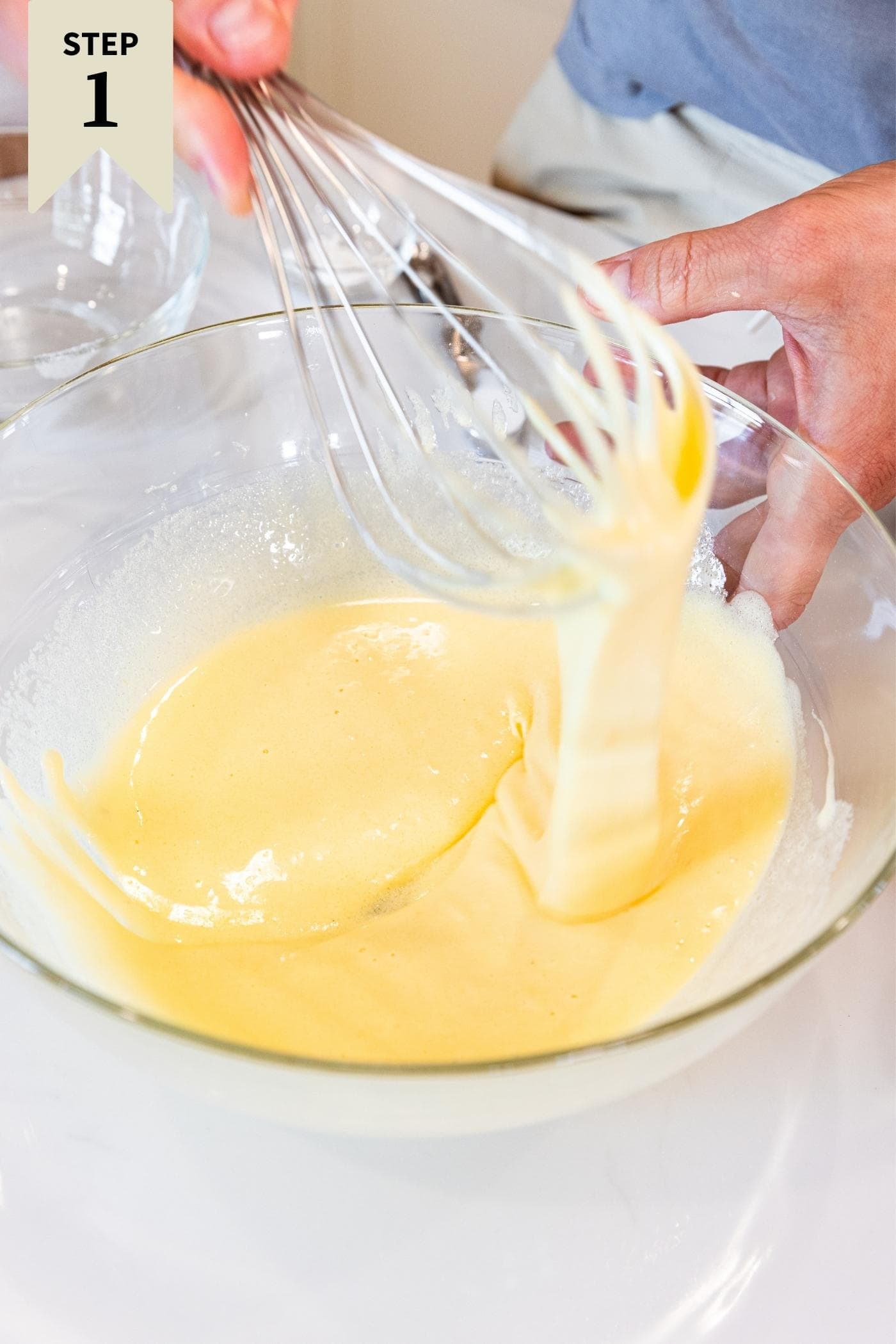 Hand using whisk to stir together sugar and butter mixture, displaying the ribbons the batter makes.
