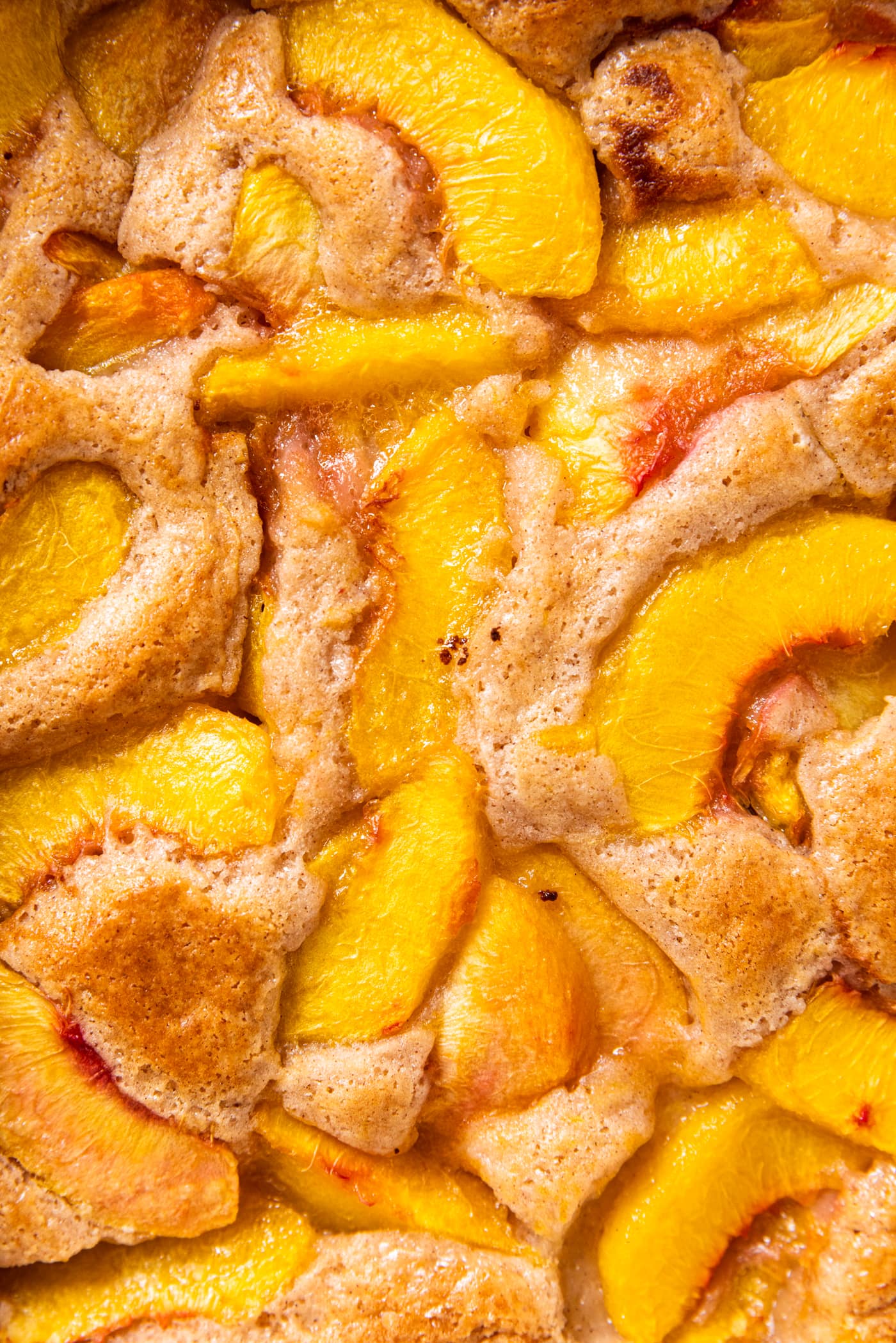 Peach cobbler showing peaches and batter.