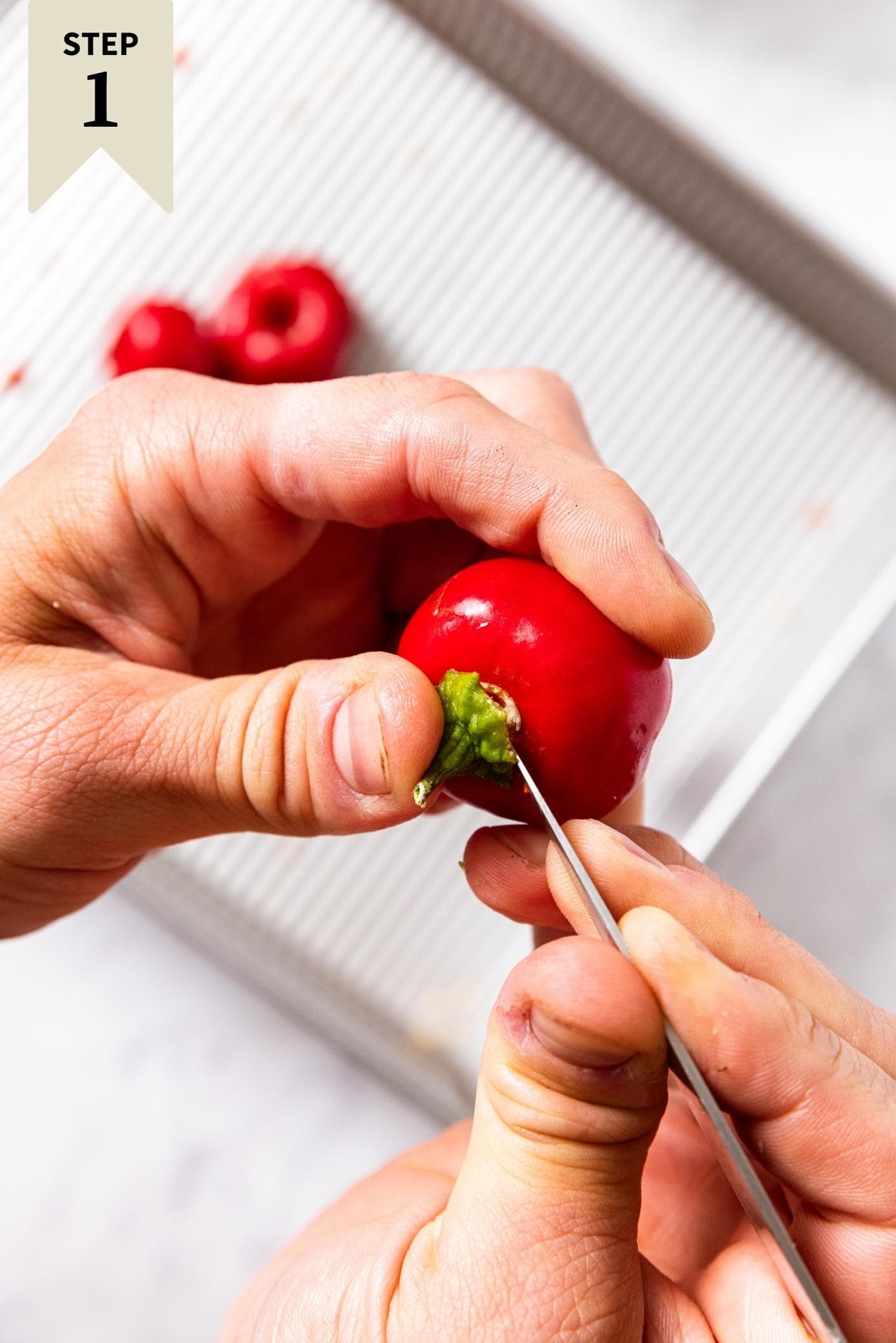 Two hands holding a knife putting the tip under the stem to try to remove it.
