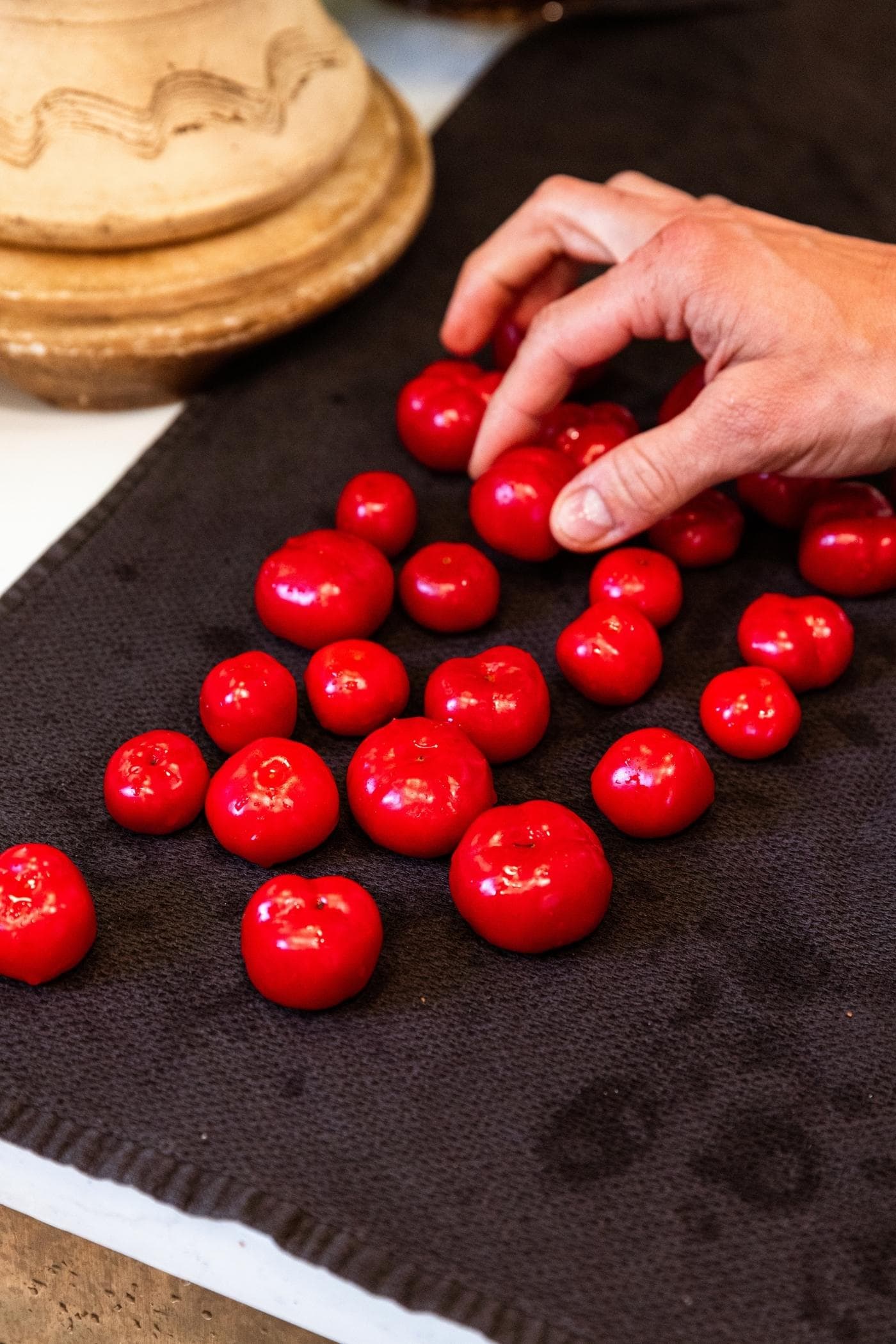 Black towel sitting on countertop with wet small red sweet peppers drying.